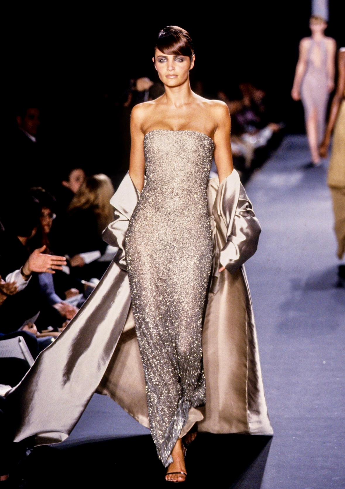 From the Fall/Winter 1997 collection, this stunning silver beaded gown Halston gown, designed by Randolph Duke, debuted on the season’s runway, modeled by Helena Christensen. Covered in metal thread, silver beads, and sequins all done by hand, this