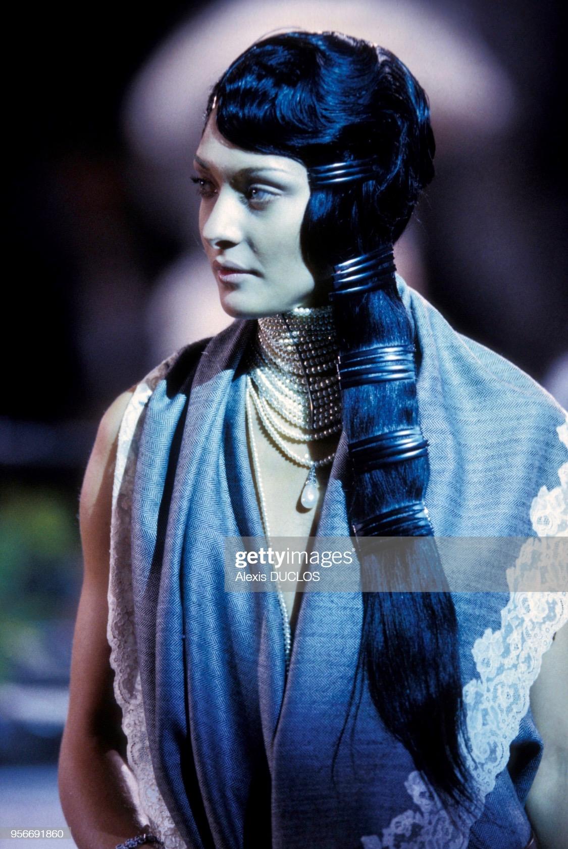 Collectional présente un tailleur jupe bordé de dentelle conçu par John Galliano pour la collection automne/hiver 1998 de Christian Dior. Une version grise de ce motif de dentelle a été présentée à plusieurs reprises lors du défilé de