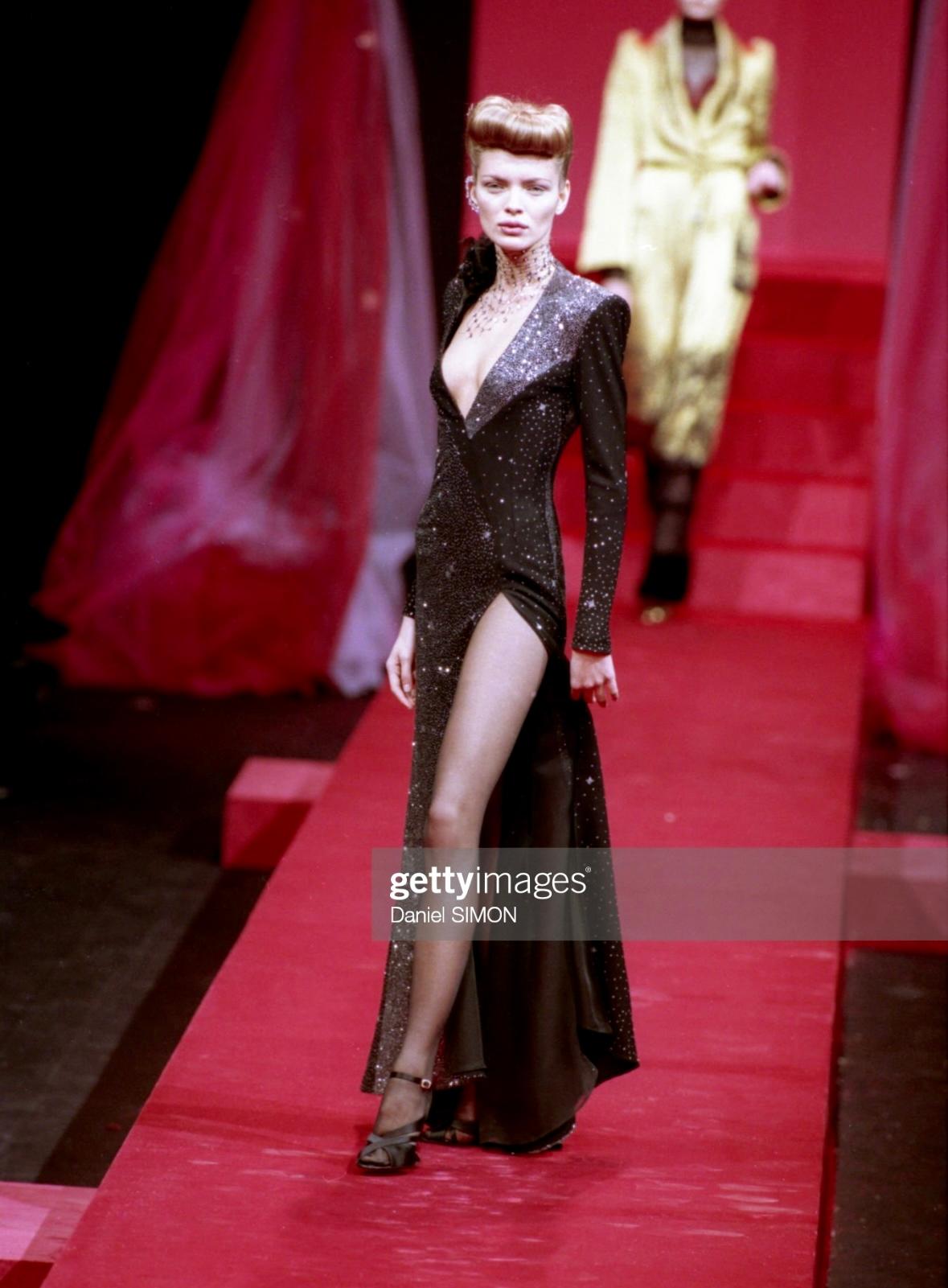 Presenting a fabulous black and silver glitter Christian Lacroix gown. From the Fall/Winter 1998 collection, this beautiful dress debuted on the season's runway on Esther Cañadas. This unique asymmetric dress features shoulder pads, a deep neckline,