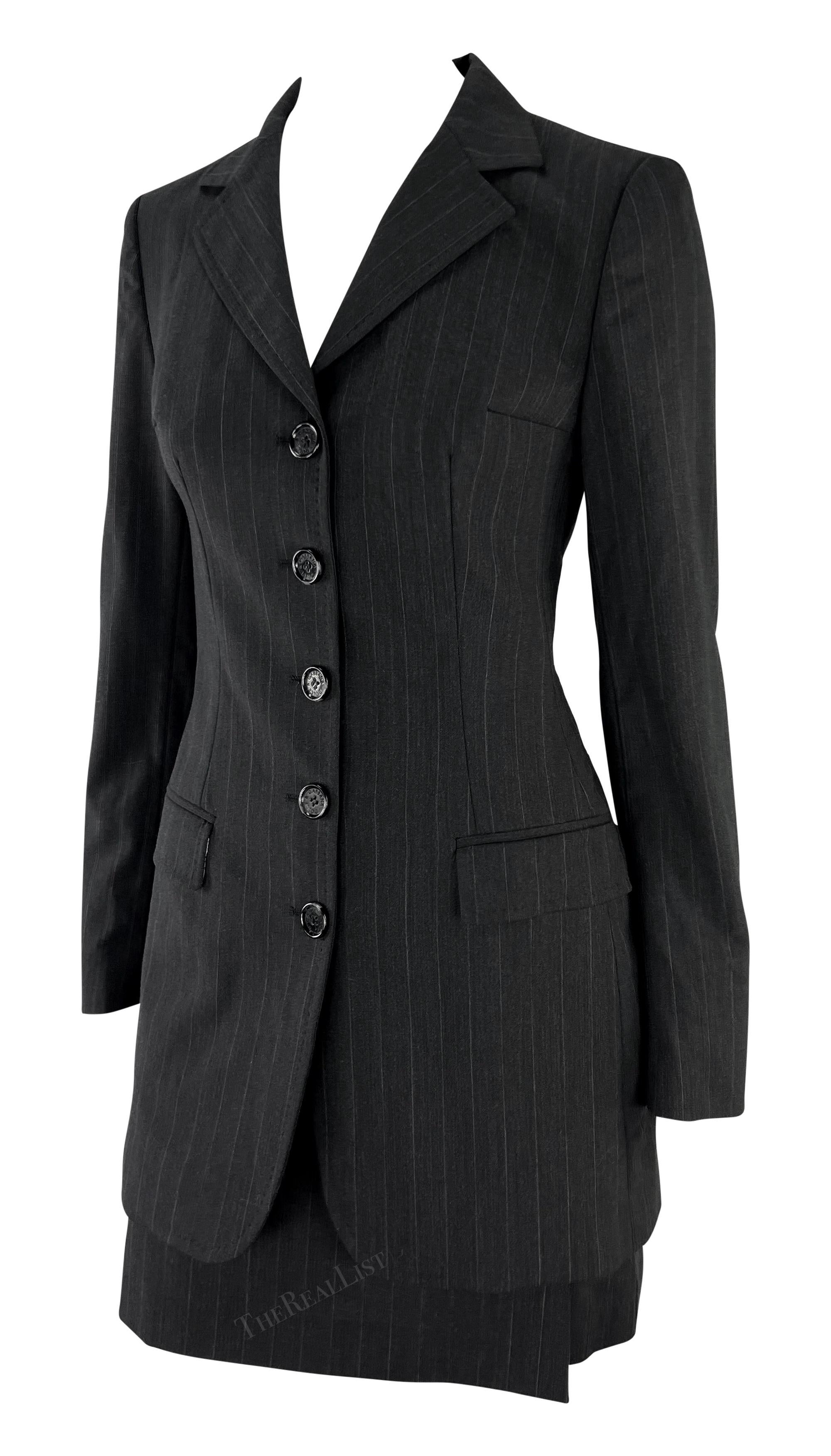 This chic grey pinstripe mini skirt suit set is from Dolce & Gabbana's Fall/Winter 1998 collection. The set includes a long blazer with a classic pinstripe pattern and a matching high-waisted mini skirt. Chic, sexy, yet sophisticated, this vintage