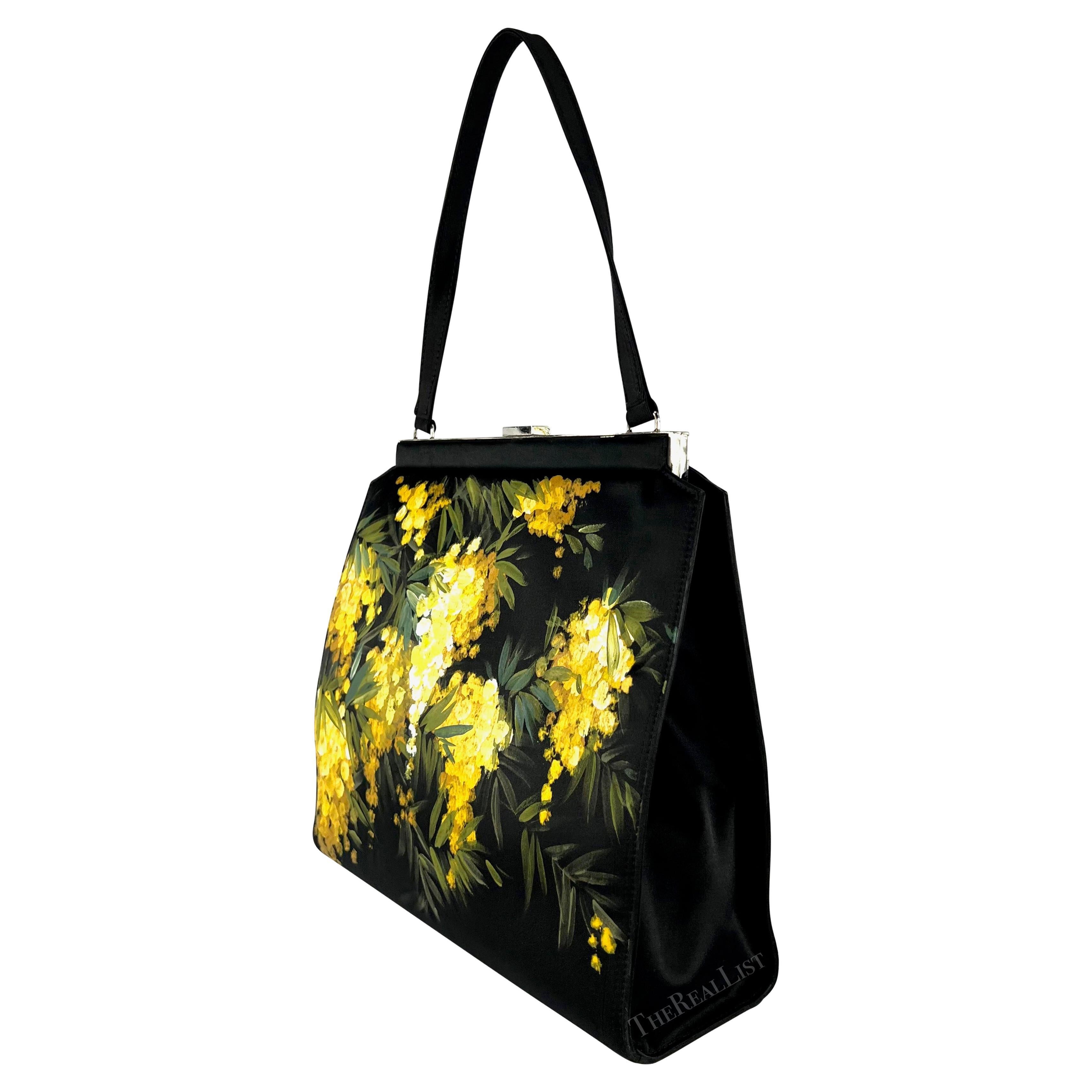 Presenting a stunning black satin Dolce & Gabbana top handle bag. From the Fall/Winter 1998 collection, this black satin bag features silver-tone hardware and a clamshell closure. The bag is elevated with a hand-painted yellow floral butterfly