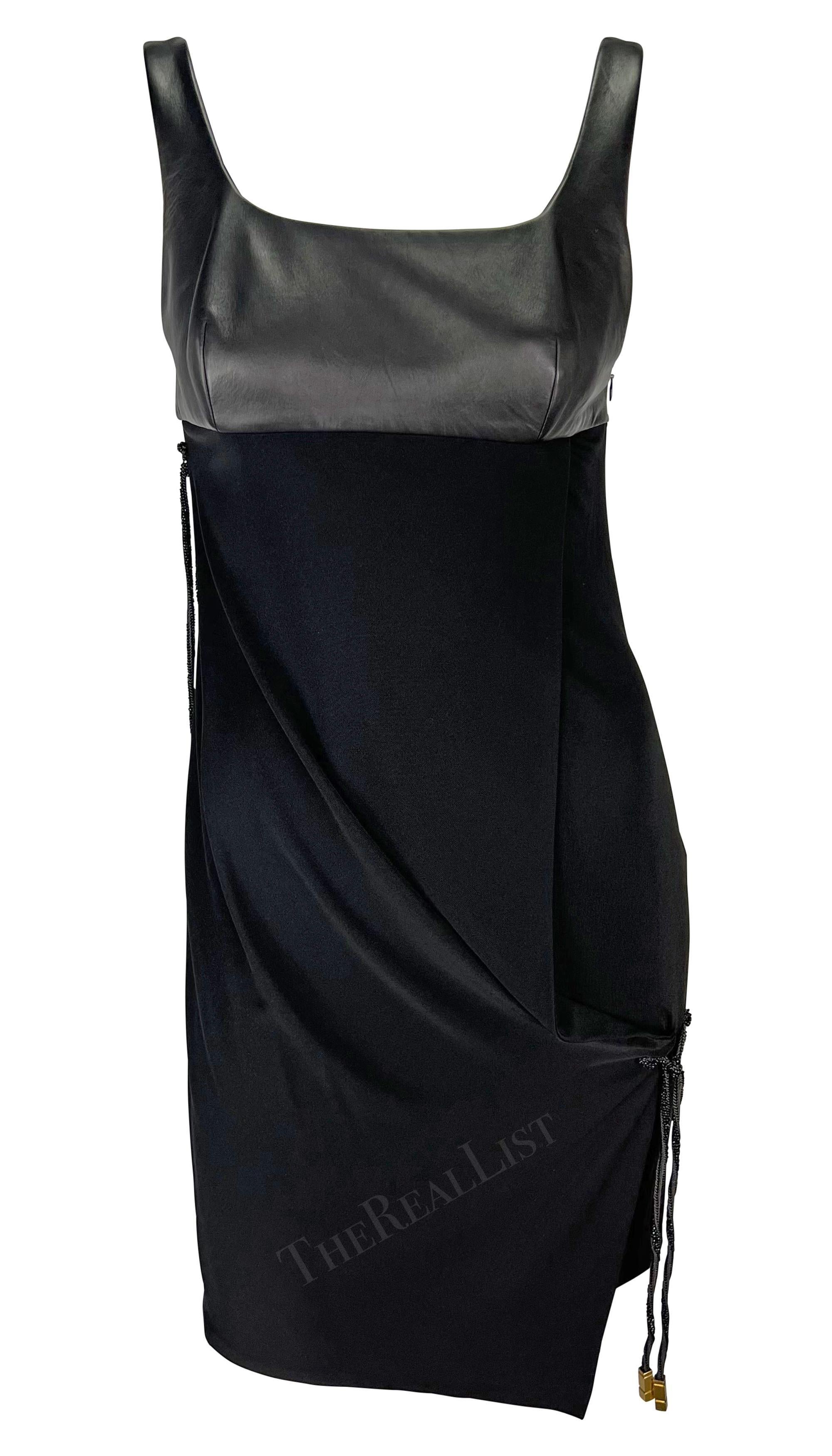 Ti presentiamo un favoloso mini abito nero di Gianni Versace, disegnato da Donatella Versace. Dalla collezione Autunno/Inverno 1998, questo abito senza maniche presenta un busto in pelle e una scollatura a palloncino. L'abito è completo di accenti