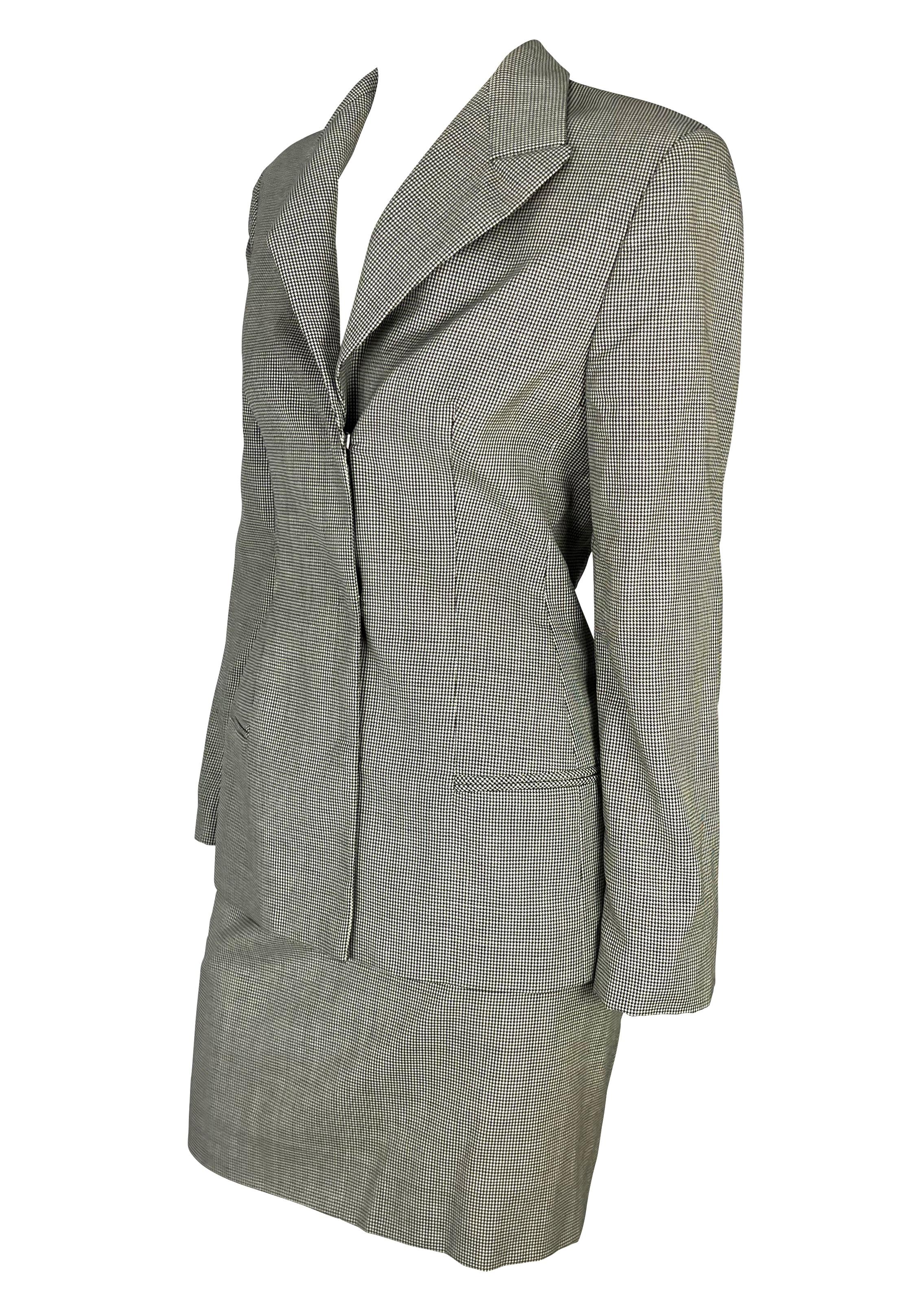Presenting a grey houndstooth Gianni Versace skirt suit, designed by Donatella Versace. From the Fall/Winter 1998 collection, this fabulous skirt suit features hidden hook closures on the blazer, a draped detail at the back of the blazer, and a