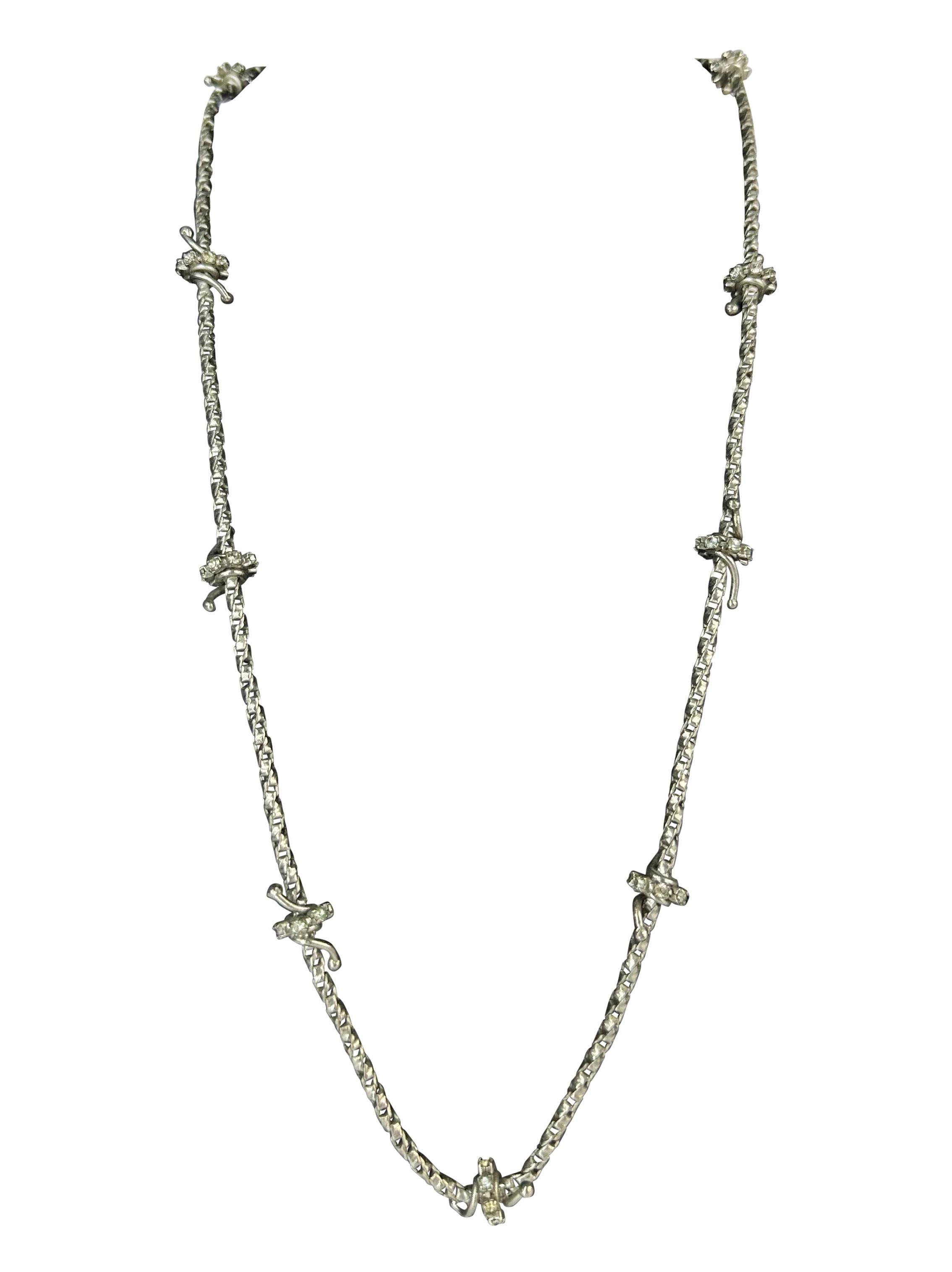 Voici un collier Gianni Versace à fil dénudé, orné de strass en argent, conçu par Donatella Versace. Issu de la collection Automne/Hiver 1998, ce collier est constitué d'une fine chaîne en métal argenté avec des détails métalliques enveloppés et