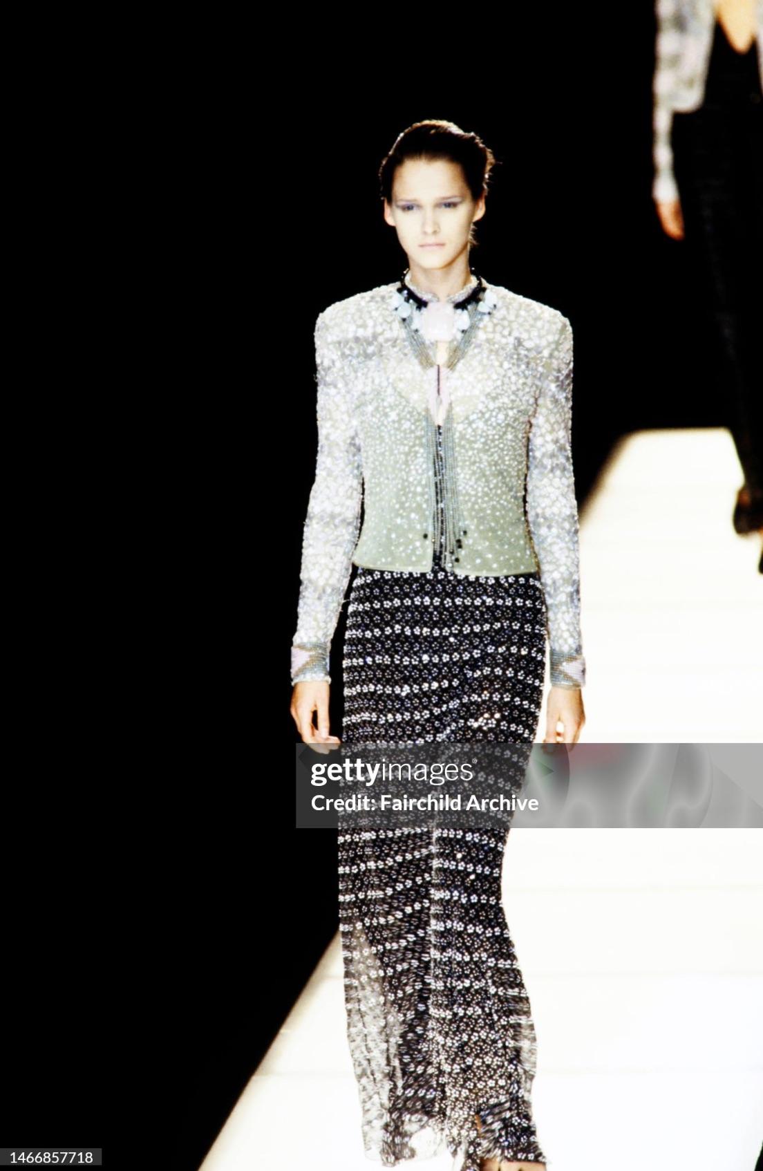 This Giorgio Armani gown is crafted from black silk with intricate silver beading. The abstract floral beading technique debuted on the Fall/Winter 1998 runway on a similar dress worn by Carmen Kass. This sleeveless design features a faux wrap