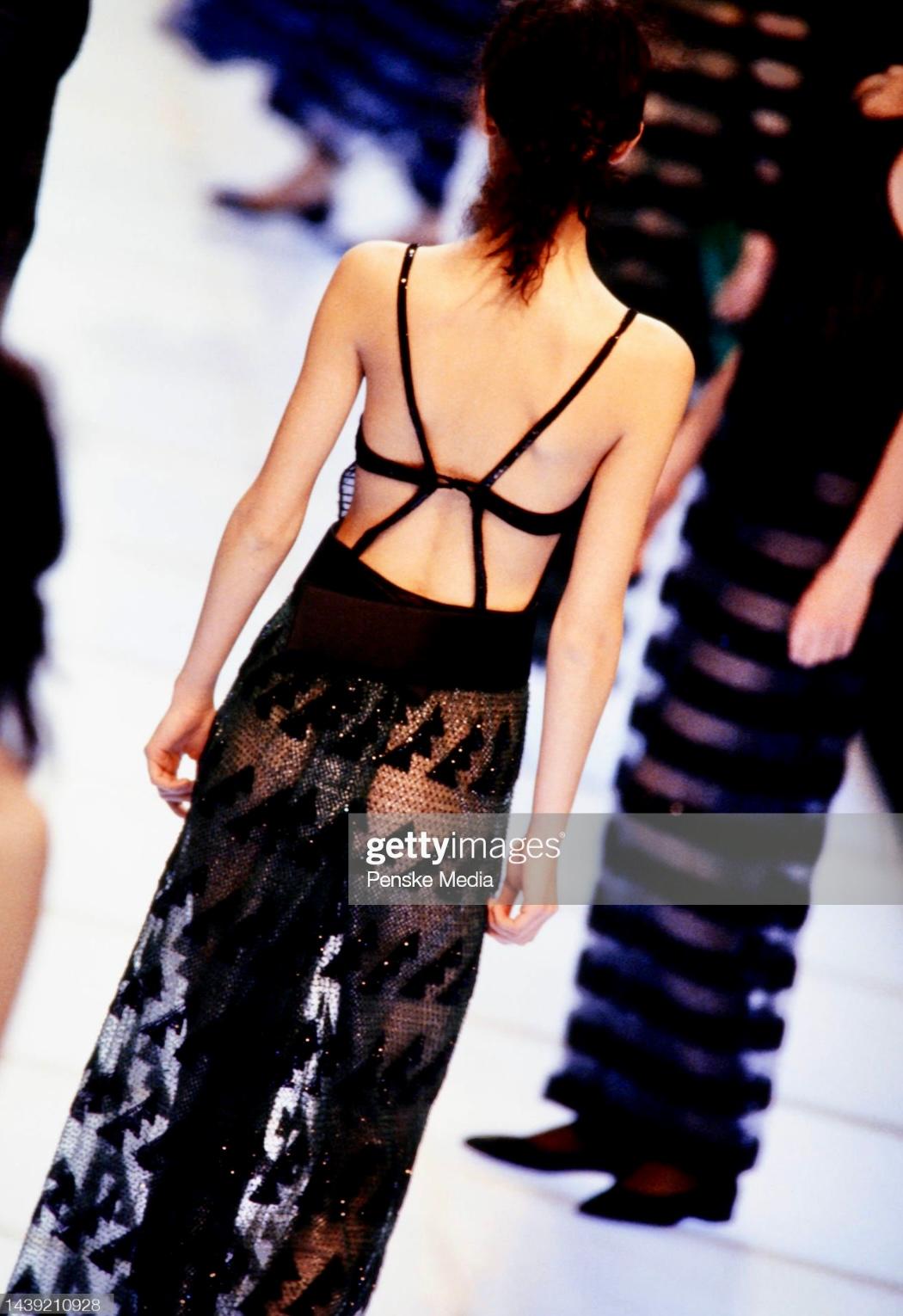 Presenting a captivating black velvet Giorgio Armani crop top from the Fall/Winter 1999 collection is a luxurious piece. Constructed from soft black velvet, this alluring top features an enticing strap design that graced the season's runway.