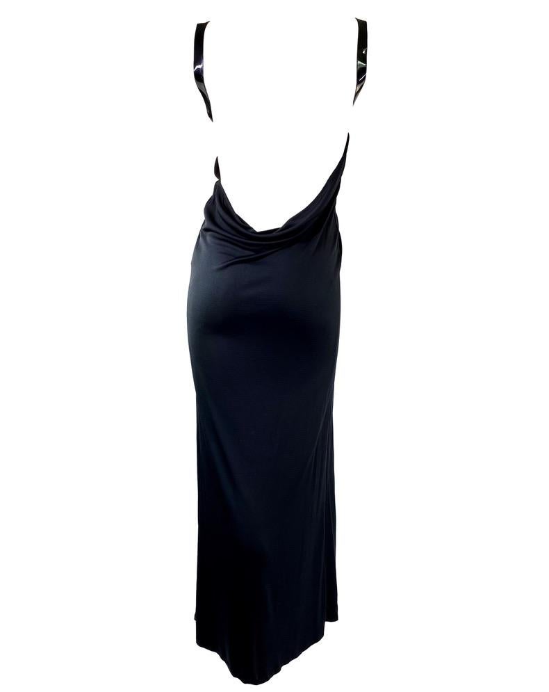 Presenting a gorgeous black backless Gucci gown, designed by Tom Ford. From the Fall/Winter 1999 collection, this dress is constructed of satin silk, which drapes over the body. Made complete with a patent leather accent, the leather strap outlines