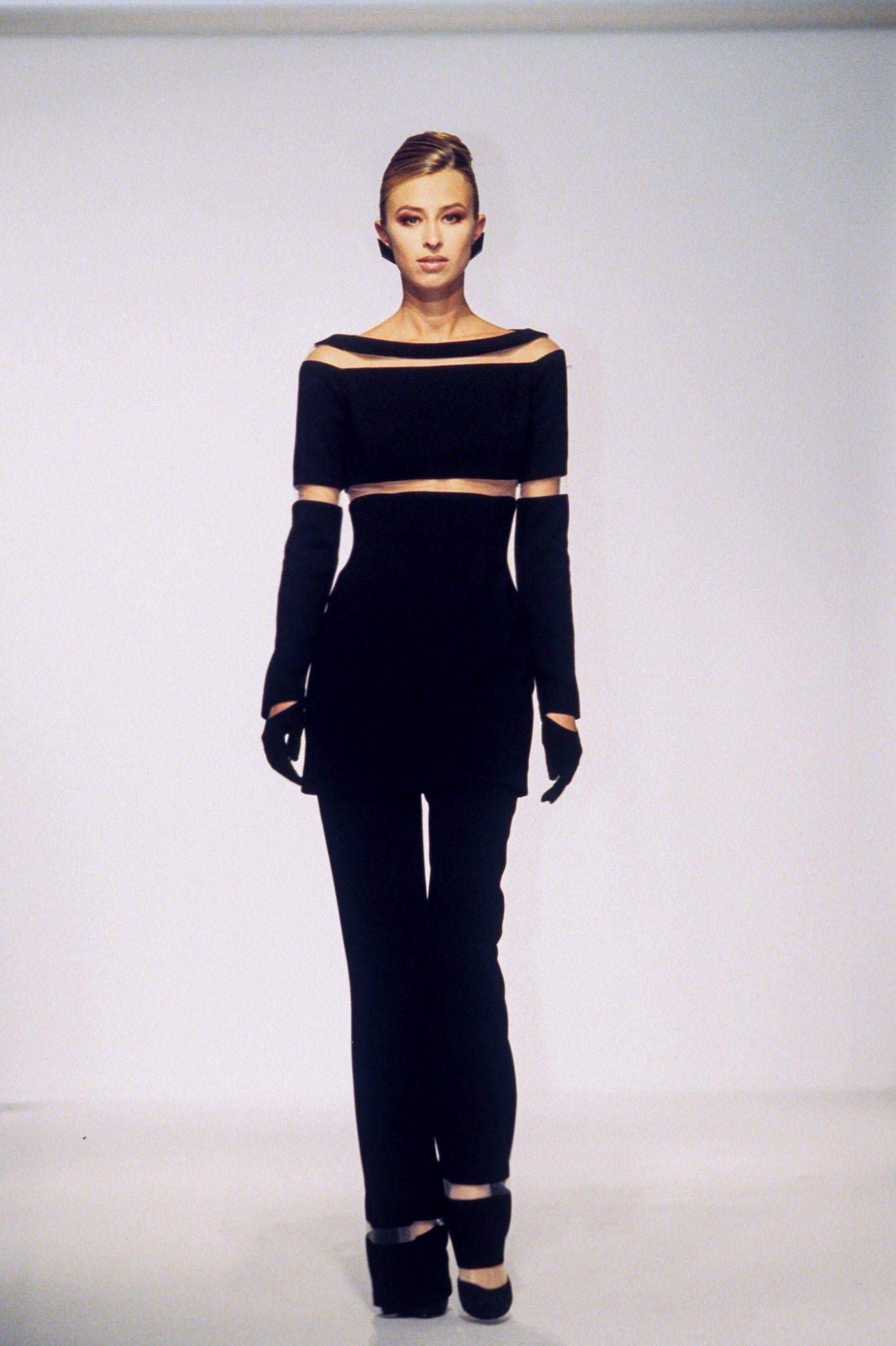 Dalla collezione Autunno/Inverno 1999, questo favoloso mini abito nero di Thierry Mugler, disegnato da Manfred Mugler, ha debuttato sulla passerella della stagione con una lunghezza media. Presenta sottili pannelli in rete beige che attraversano il