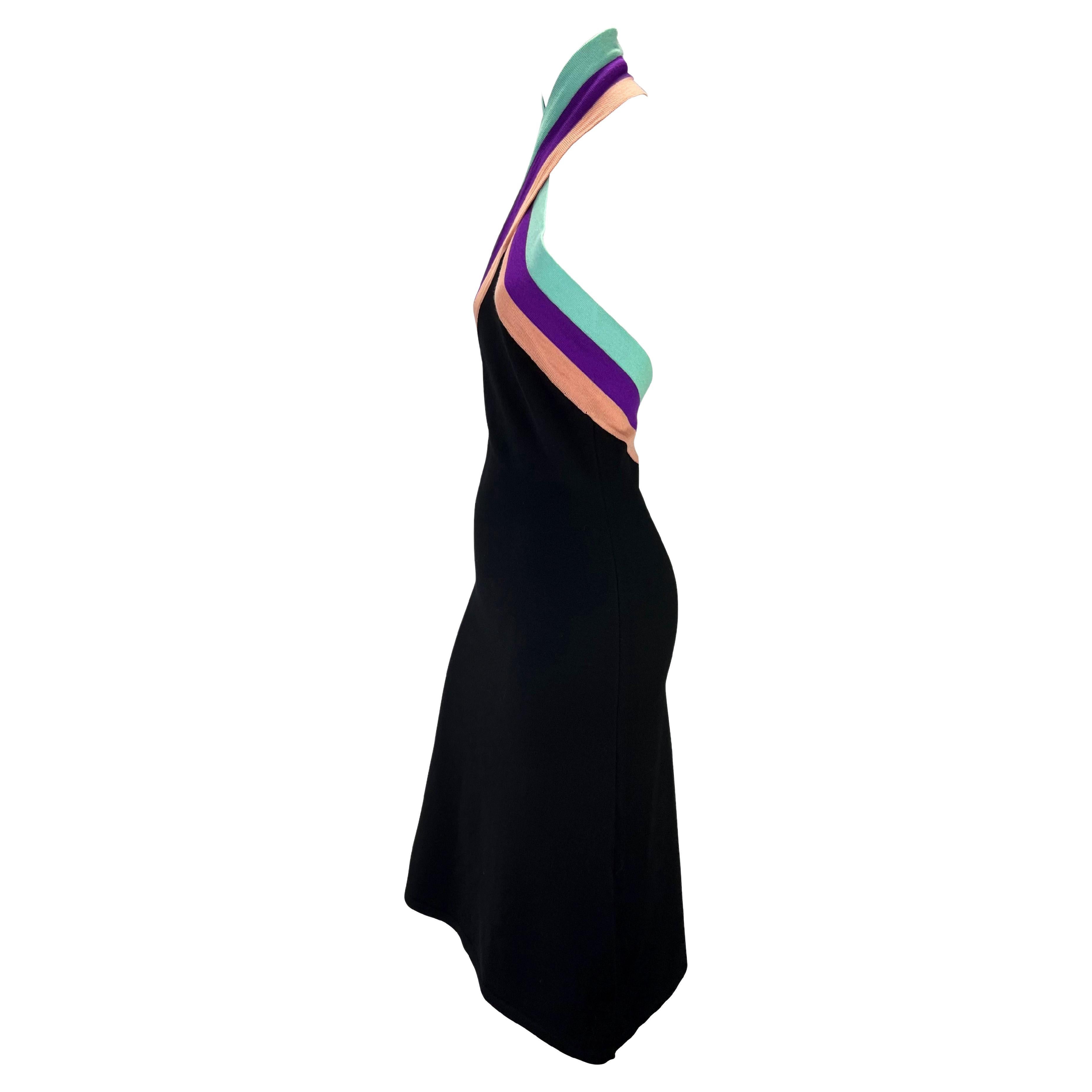 Présentation d'une robe dos nu en maille extensible moulante conçue par Donatella pour la collection automne/hiver 2000 de Gianni Versace. L'encolure dos nu croisée est rehaussée d'une rangée de six boutons en strass irisés. Cette robe est une