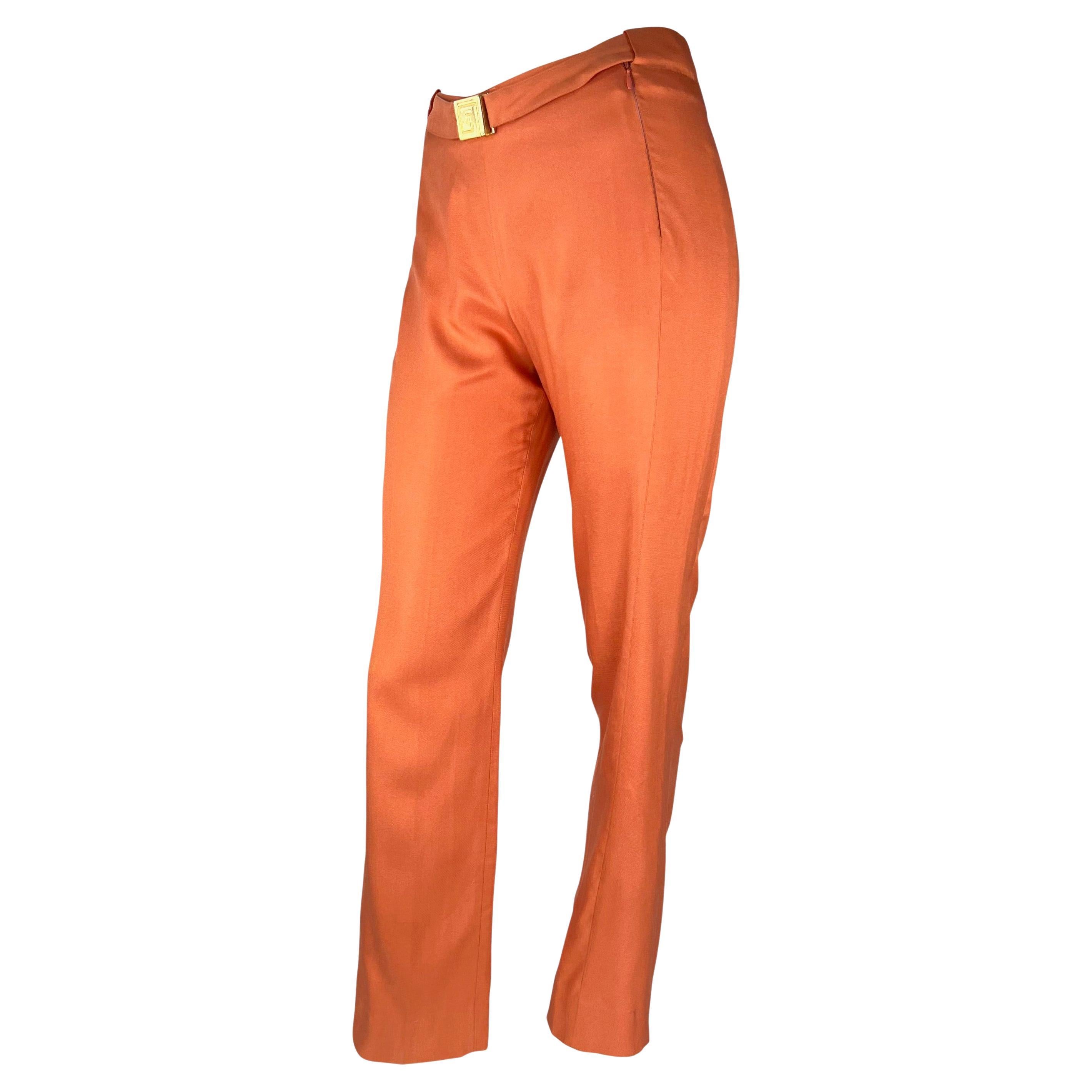 Presenting a pair of vibrant orange Gianni Versace Couture pants, designed by Donatella Versace. From the Fall/Winter 2000 collection, these wide-leg pants are constructed entirely of orange silk and are made complete with a built-in belt with a