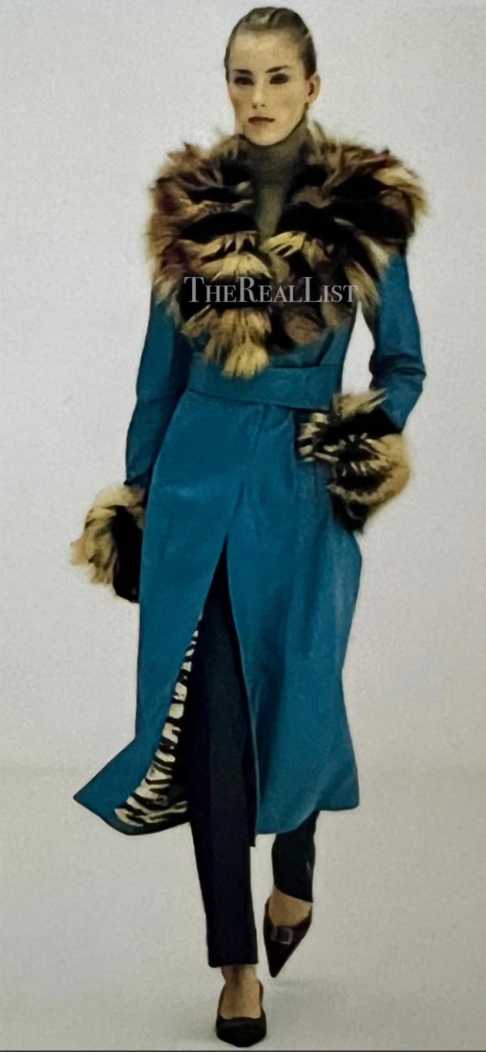 Presenting a stunning blue leather Dolce & Gabbana trench coat. From the Fall/Winter 2001 collection, this coat made its runway debut as part of look 44. Constructed of bright blue leather, this coat is accented with black and orange striped fox fur