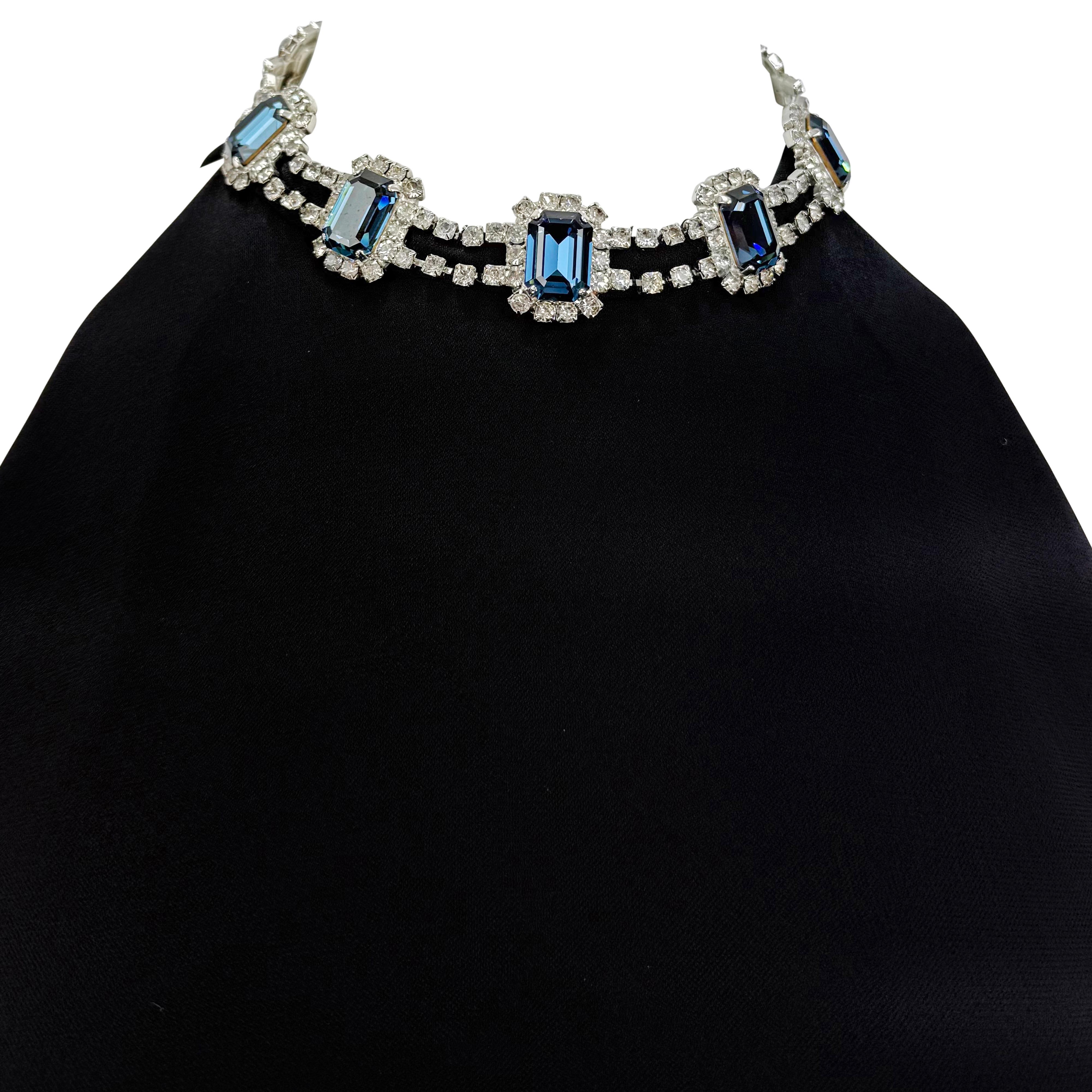 Dalla collezione Dolce & Gabbana per l'Autunno/Inverno 2001, questo top senza maniche nero elasticizzato presenta una collana di strass con decorazioni in cristallo blu e trasparente. Progettato con una scollatura alta, il top si apre su una