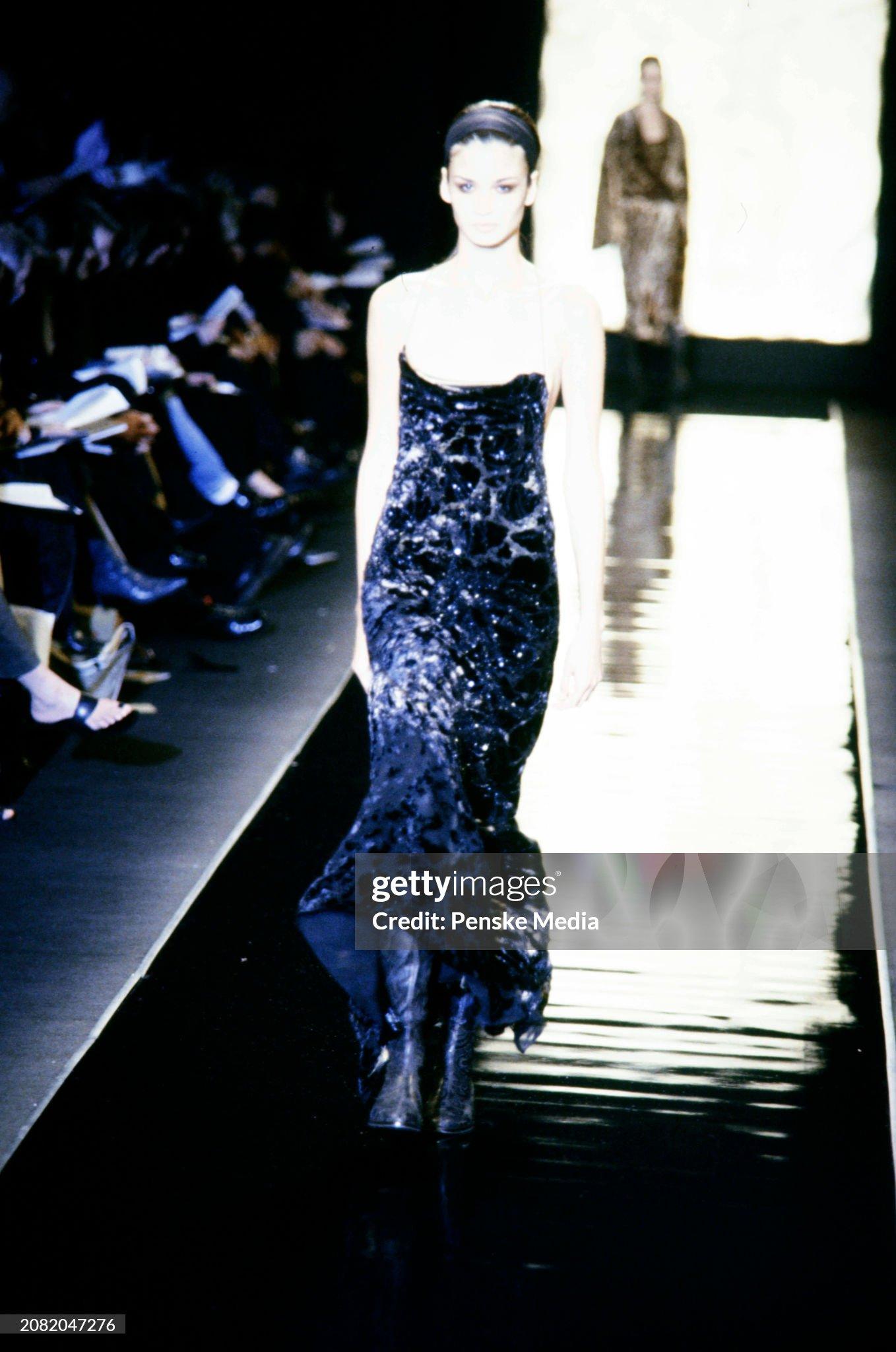 This golden lamé slip gown, from Donna Karan's Fall/Winter 2001 collection, made its debut on the runway as part of look 72 on Caroline Ribeiro. Crafted from luxurious gold lamé fabric, this floor-length gown is adorned with a black velvet devoré