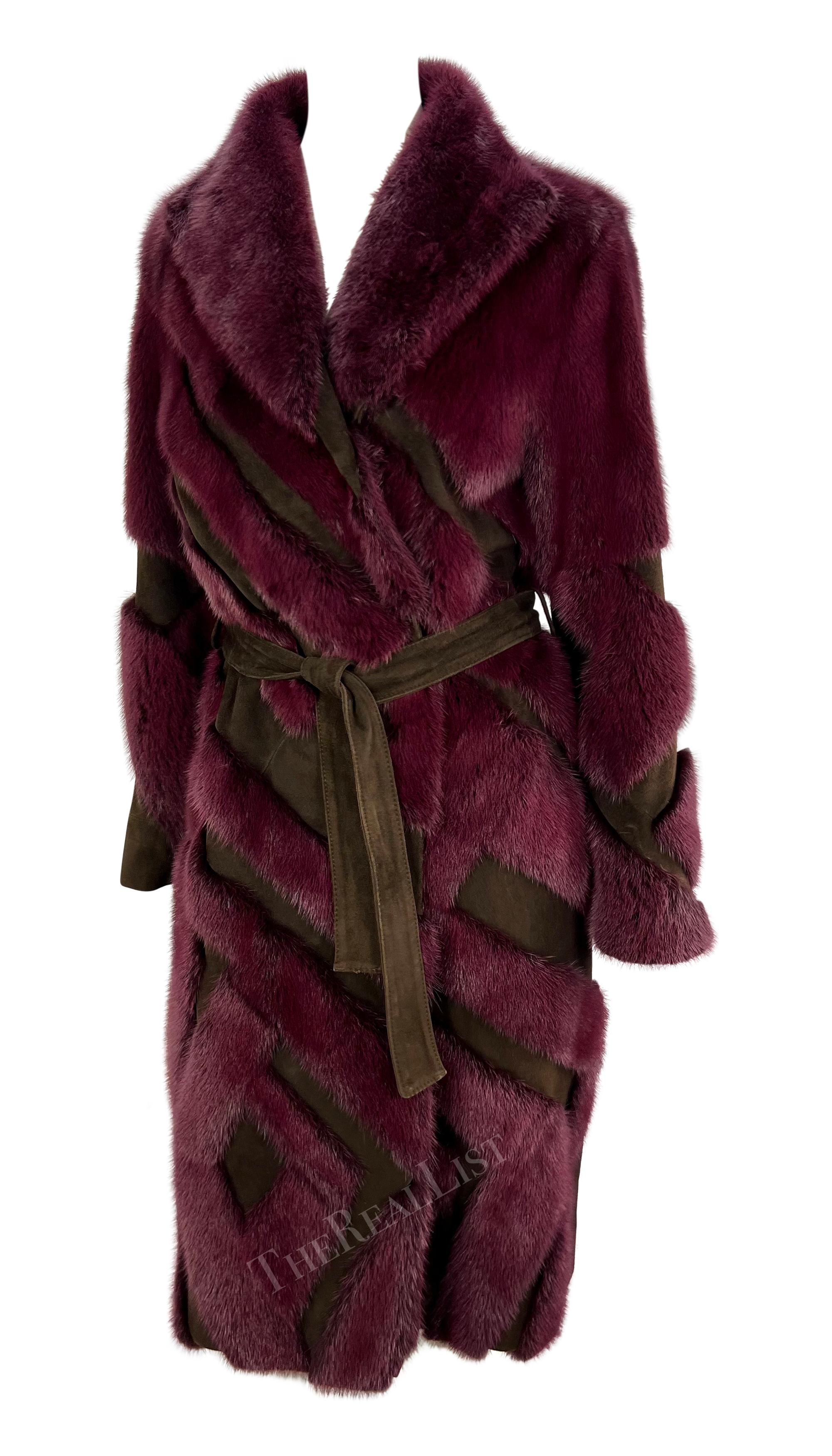 This Fall/Winter 2001 Gianni Versace by Donatella trench coat is crafted from luxurious purple mink fur with brown suede accents. The wrap-style design features a belted waist, wide lapel and long sleeves. The geometric pattern created by the mix of