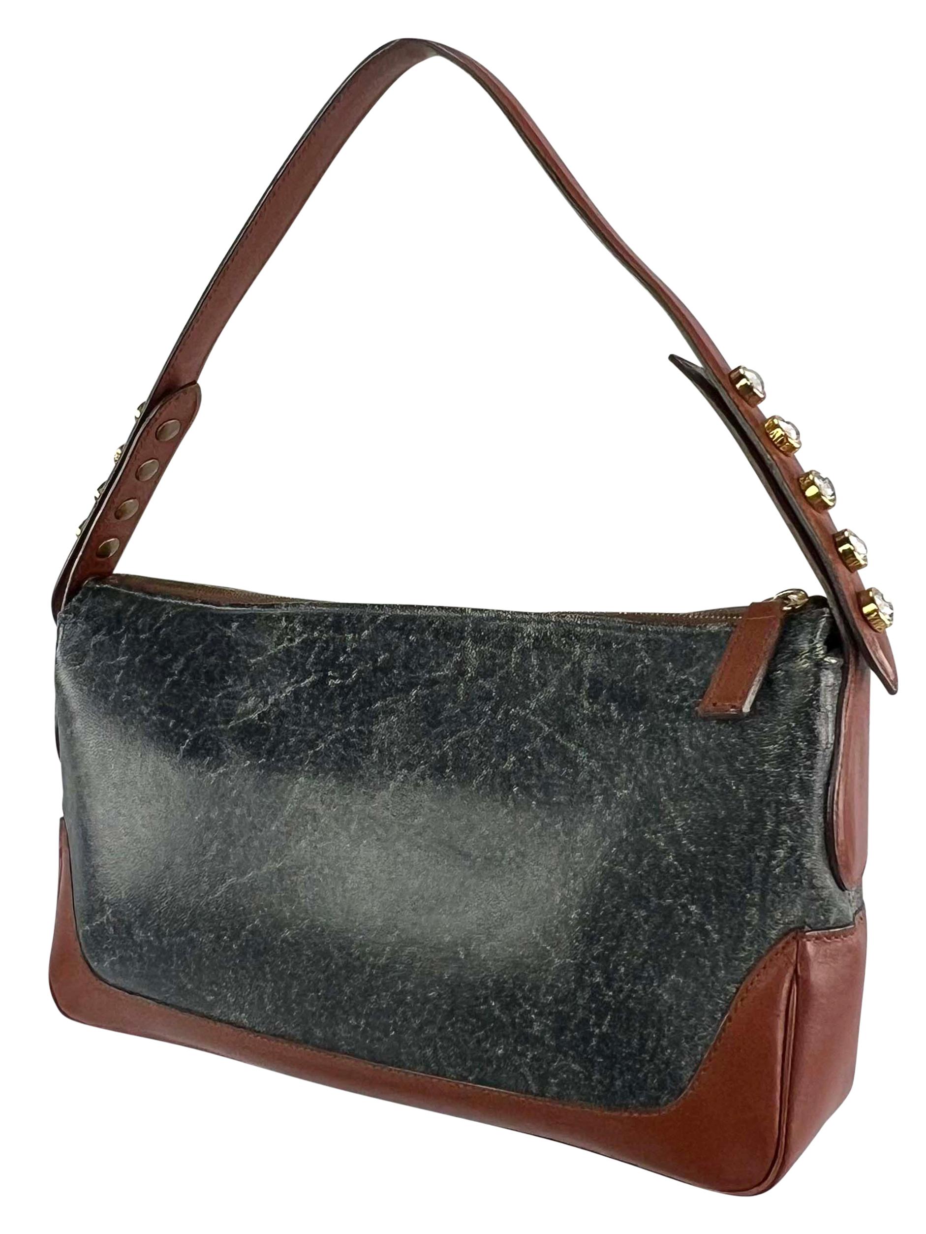 From the Fall/Winter 2001 collection, this Donatella-designed Gianni Versace shoulder bag is constructed of blue lightly distressed leather with brown leather trim. This chic small bag is complete with rhinestoned adjustable snaps at the strap,