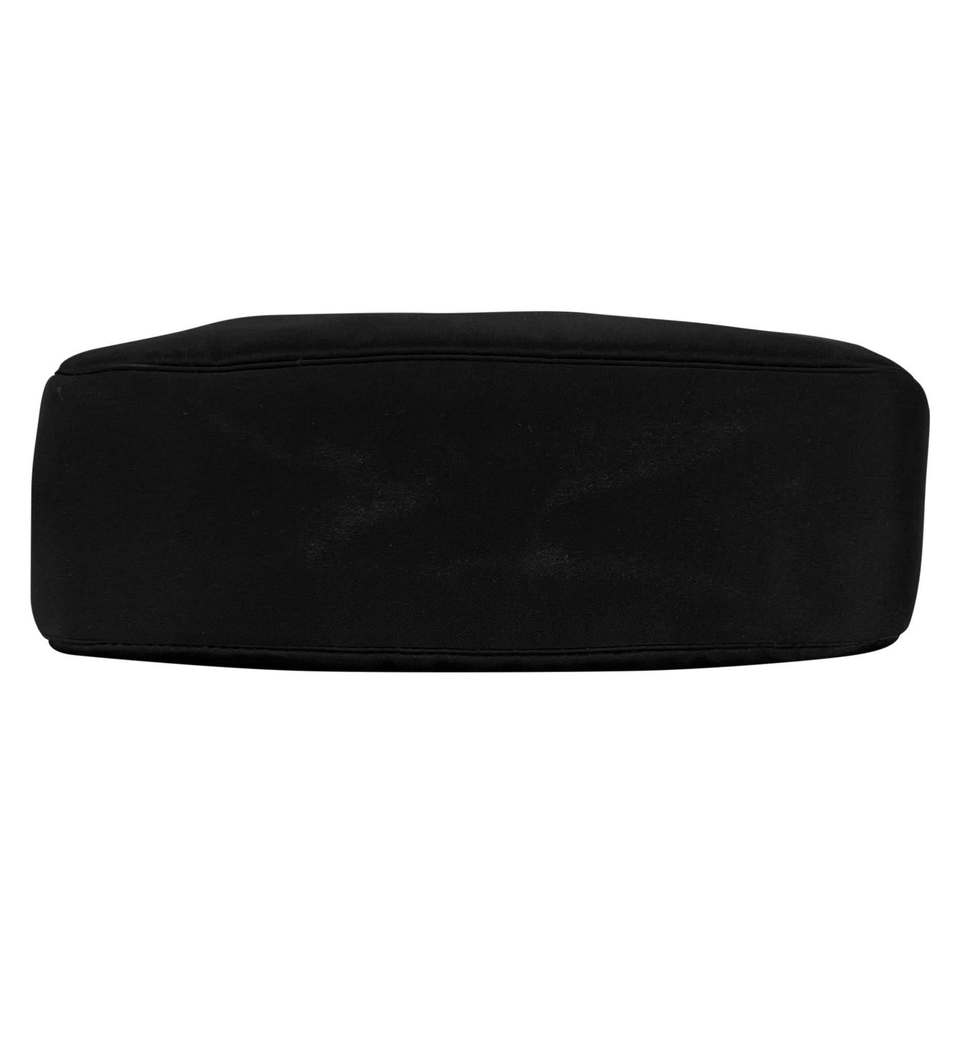 Donatella Versace ha disegnato questa elegante borsa da sera in raso nero per la collezione Autunno/Inverno 2001 di Gianni Versace. Questa incantevole mini borsa presenta un corpo elegante in raso con cinghie collegate da un hardware angolare in