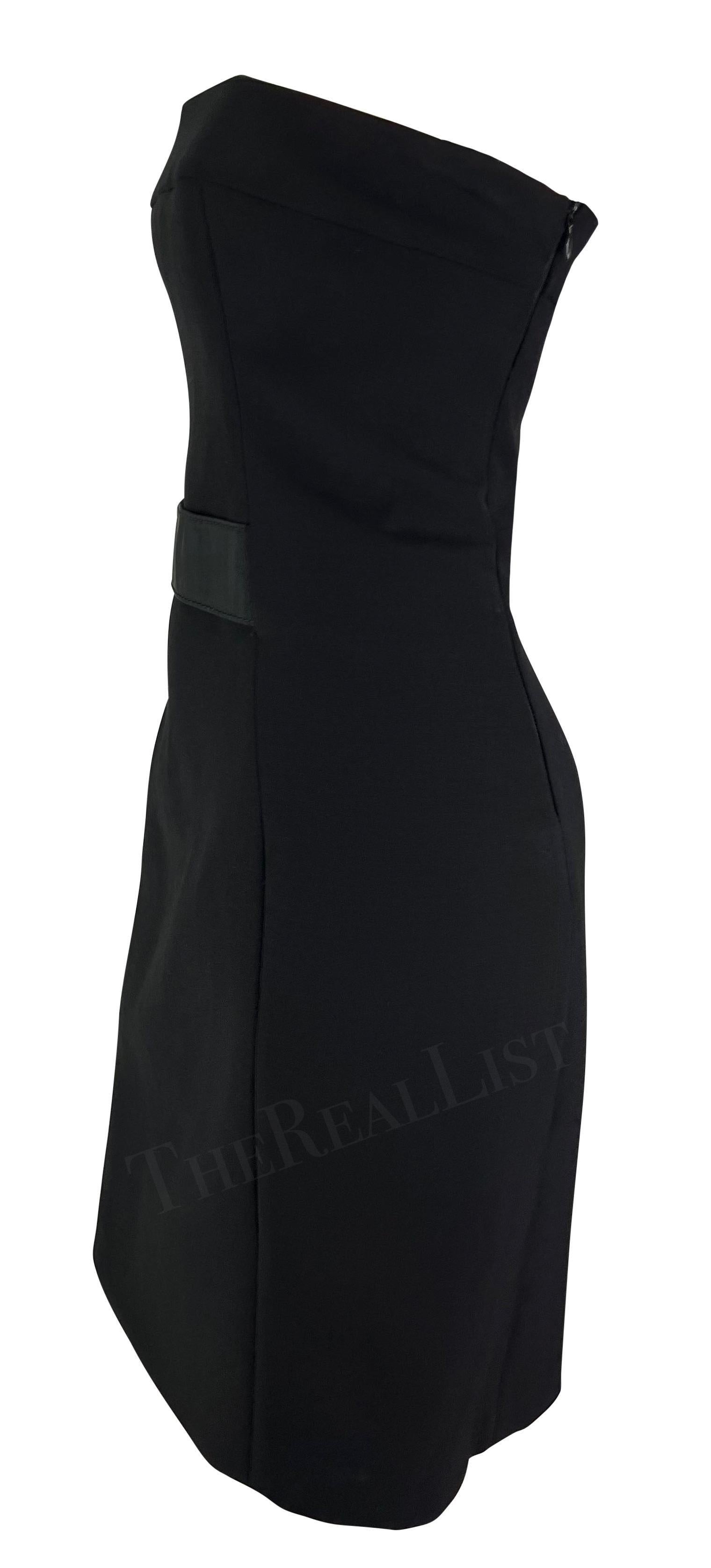 Présentation d'une robe bustier noire Gucci, dessinée par Tom Ford. Issue de la collection automne/hiver 2001, cette robe en laine sans bretelles est agrémentée d'une petite bride à la taille. Cette mini robe ajustée Gucci by Tom Ford est l'ajout