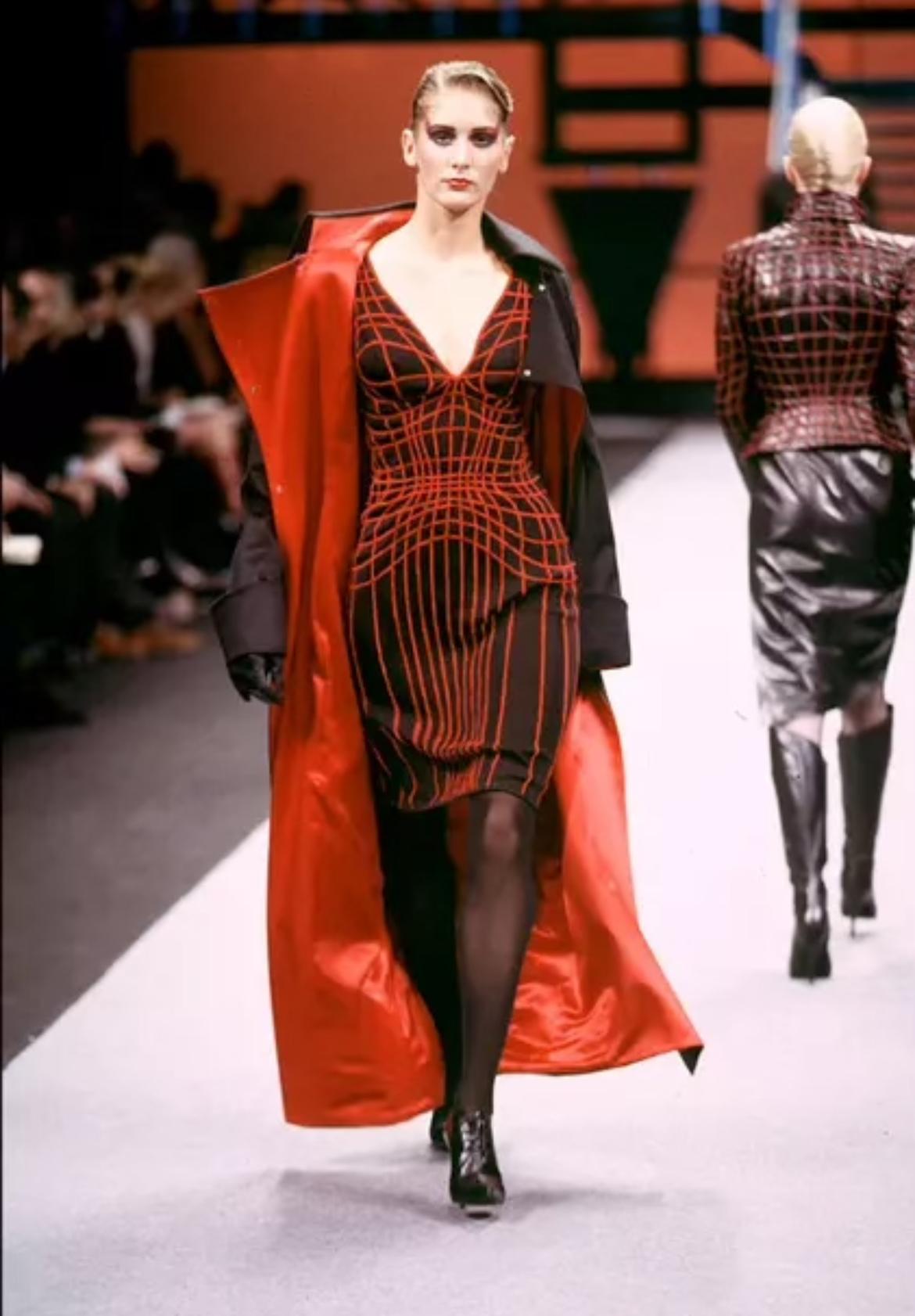 Ti presentiamo un elegante abito Thierry Mugler in maglia nera, disegnato da Manfred Mugler per la sua ultima collezione. Dalla collezione Autunno/Inverno 2001, questo favoloso mini abito è caratterizzato da maniche lunghe e scollatura a V. Una