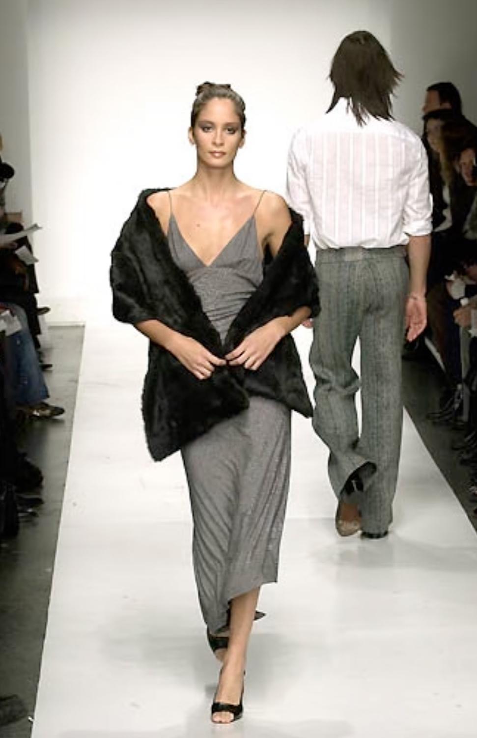 De la colección Otoño/Invierno 2001 de Yigal Azrouël, este vestido gris de espiga presenta una silueta bodycon con un escote pronunciado y una espectacular espalda abierta. Acabada con tirantes ultrafinos, un sutil fruncido entre las caderas y una