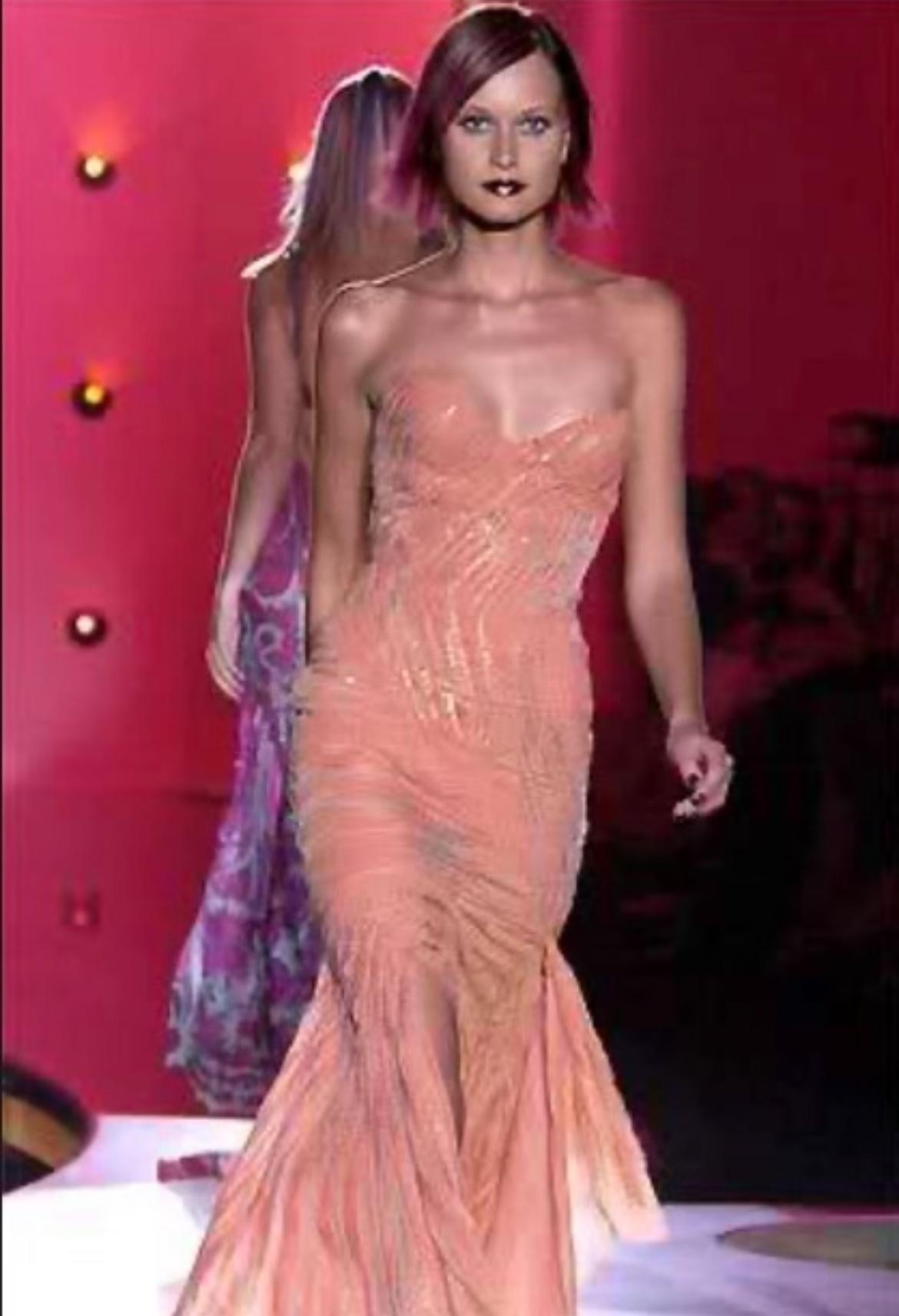 Ti presentiamo un favoloso abito Atelier Versace arancione chiaro senza spalline, disegnato da Donatella Versace. Dalla collezione Atelier Versace Autunno/Inverno 2002, questo abito ha debuttato sulla passerella della stagione come look 27,