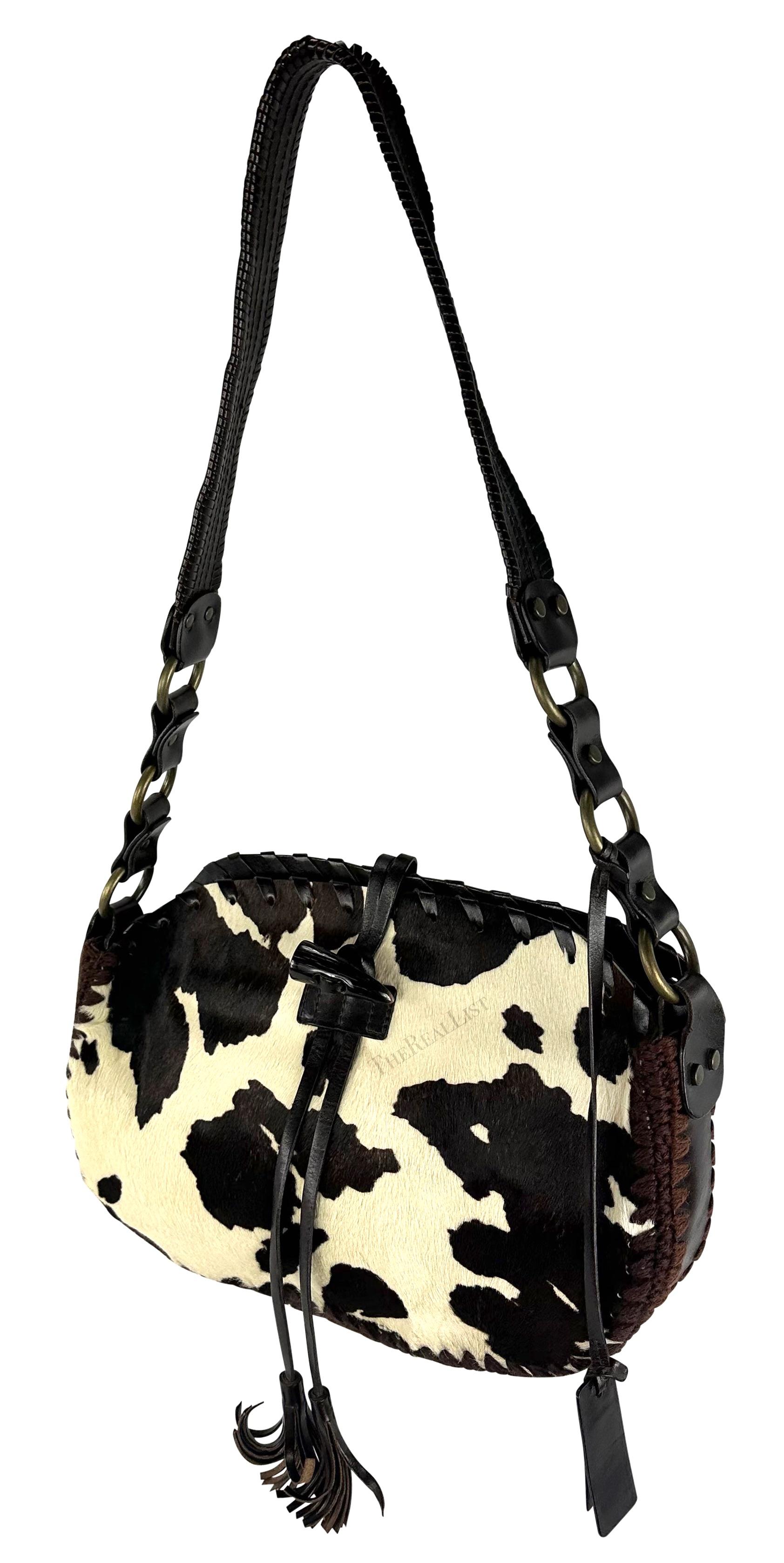 A cow print pony hair Dolce & Gabbana shoulder bag from the Fall/Winter 2002 collection. This chic small shoulder tote predominantly features cow print pony hair with dark brown leather accents. The bag features leather lace woven throughout, and