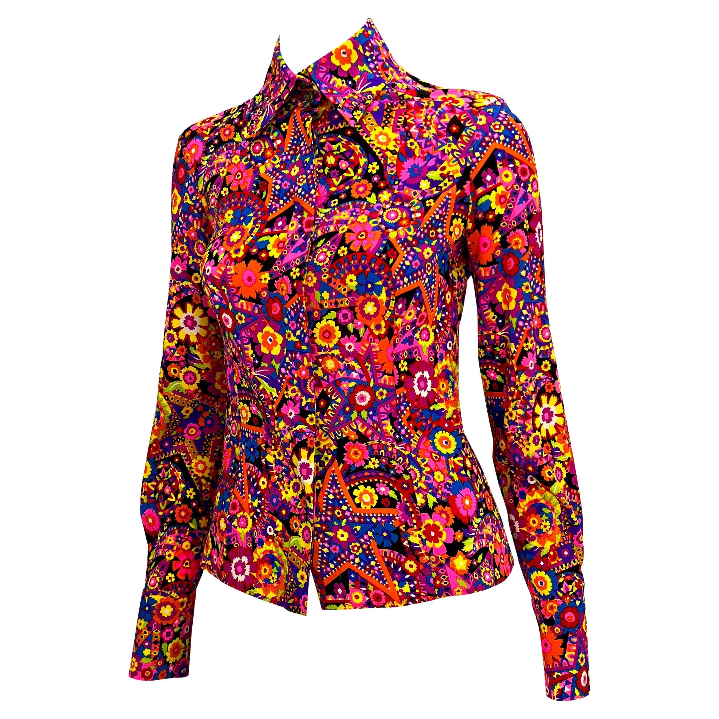 Ti presentiamo un accattivante top psichedelico disegnato da Donatella Versace per la collezione Gianni Versace Autunno/Inverno 2002. Questa blusa presenta la stampa rosa elettrico per cui è ricordata la stagione. Il top è inoltre dotato di