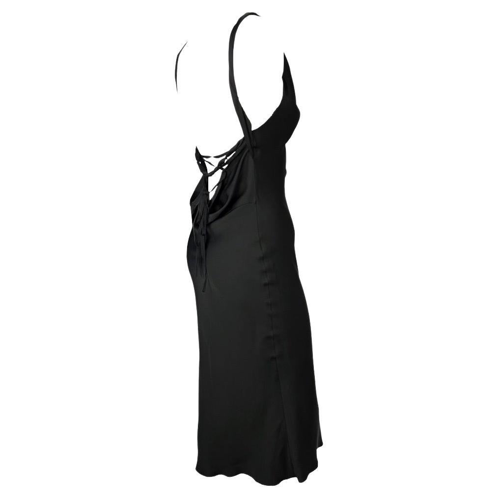Presenting a gorgeous black satin silk Gucci dress, designed by Tom Ford. From the Fall/Winter 2002 collection, this beautiful mid-length dress features a v-neckline, rolled straps, and an open cowl back with a lace tie. A step away from Ford's