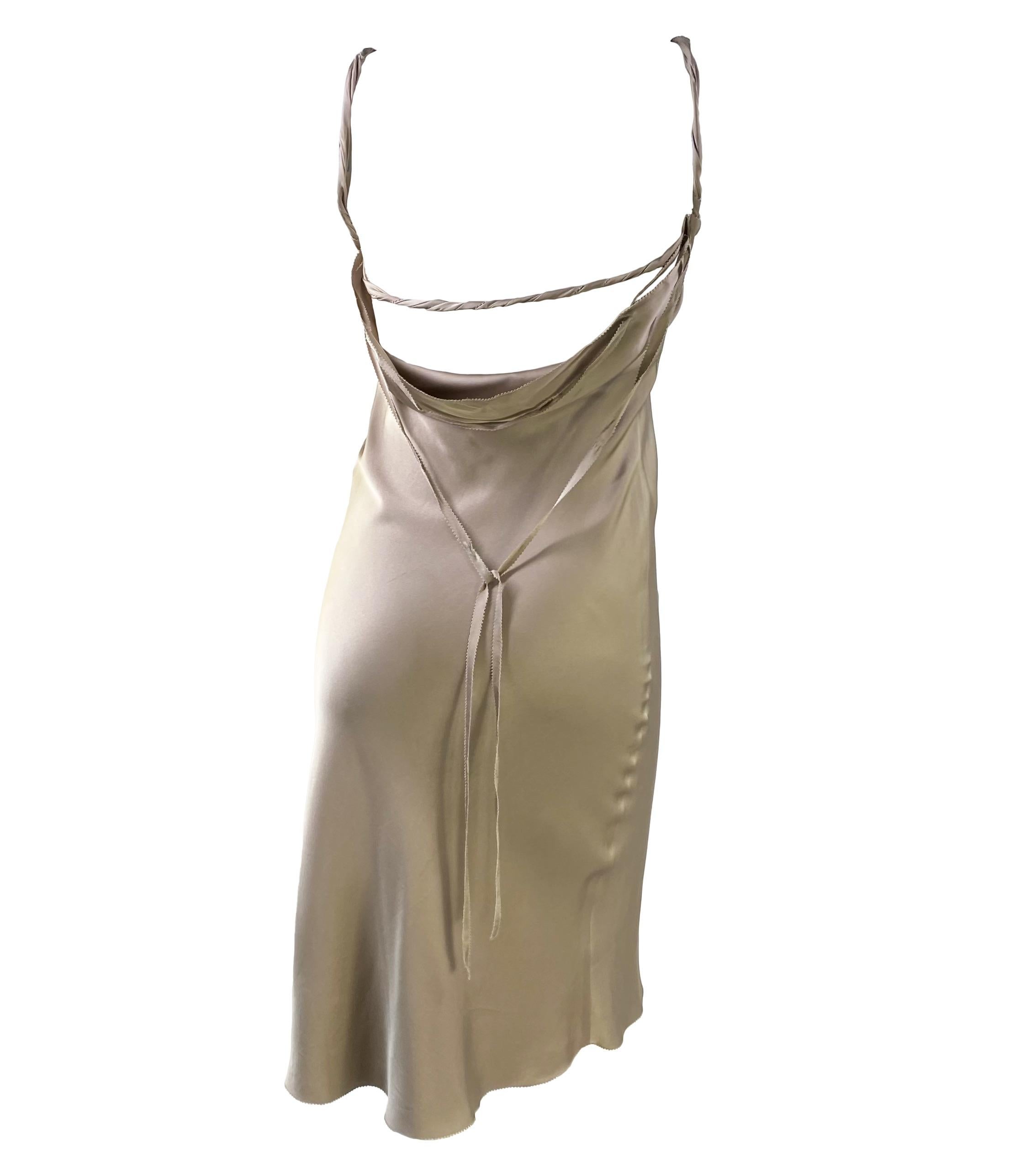 Presenting a gorgeous taupe satin silk Gucci dress, designed by Tom Ford. From the Fall/Winter 2002 collection, this beautiful mid-length dress features a v-neckline, rolled straps, and an open cowl back with a lace tie. A step away from Ford's