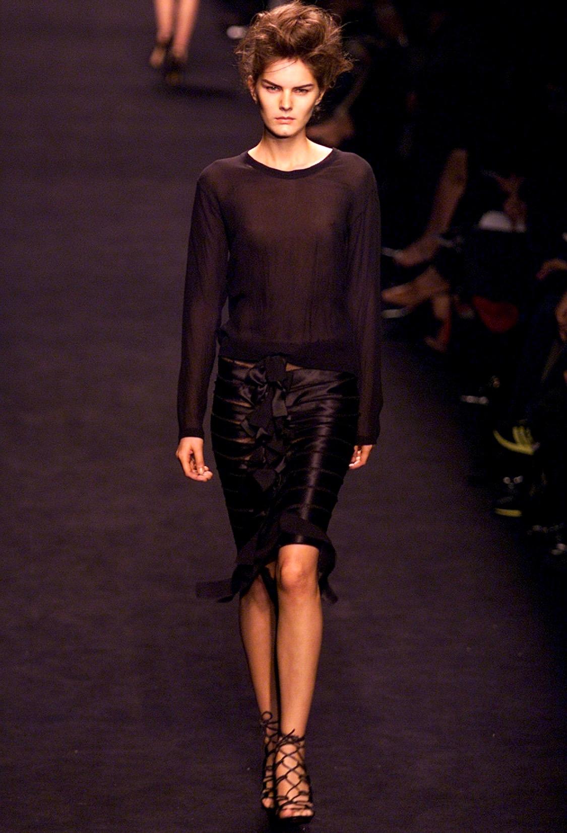 Presenting a ribbon and mesh black satin bow skirt designed by Tom Ford for Yves Saint Laurent Rive Gauche's Fall/Winter 2002 collection. Debuting as part of look 16 on Marcelle Bittar, this piece features strips of black silk ribbon sewn onto black