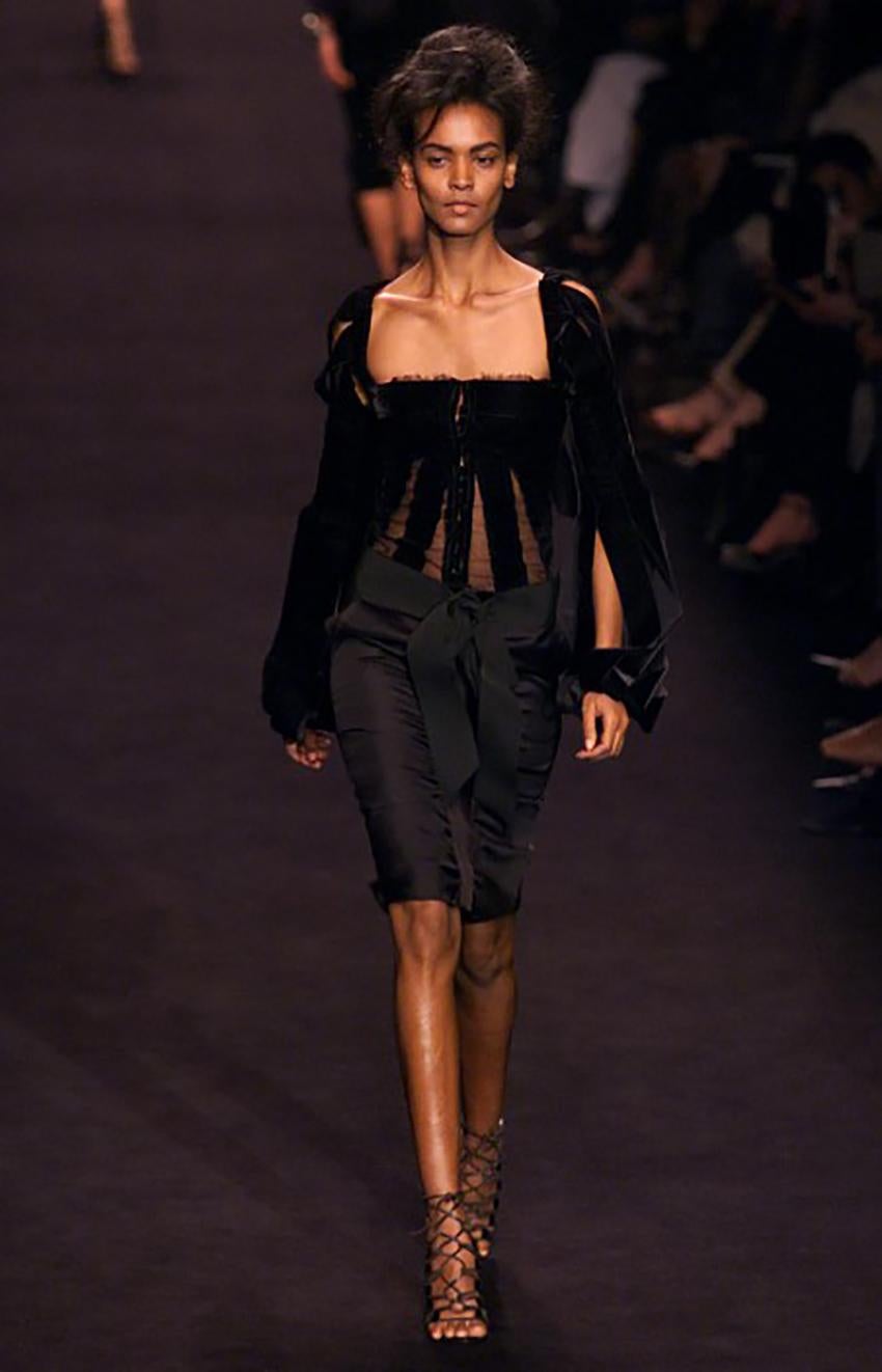 YVES SAINT LAURENT

F/W 2002 Look# 4 

The top crafted from panels of black velvet fabric is designed with a squared neckline and a corset body that features mesh cutouts and a center front hook and eye closure. The top also comes with bishop