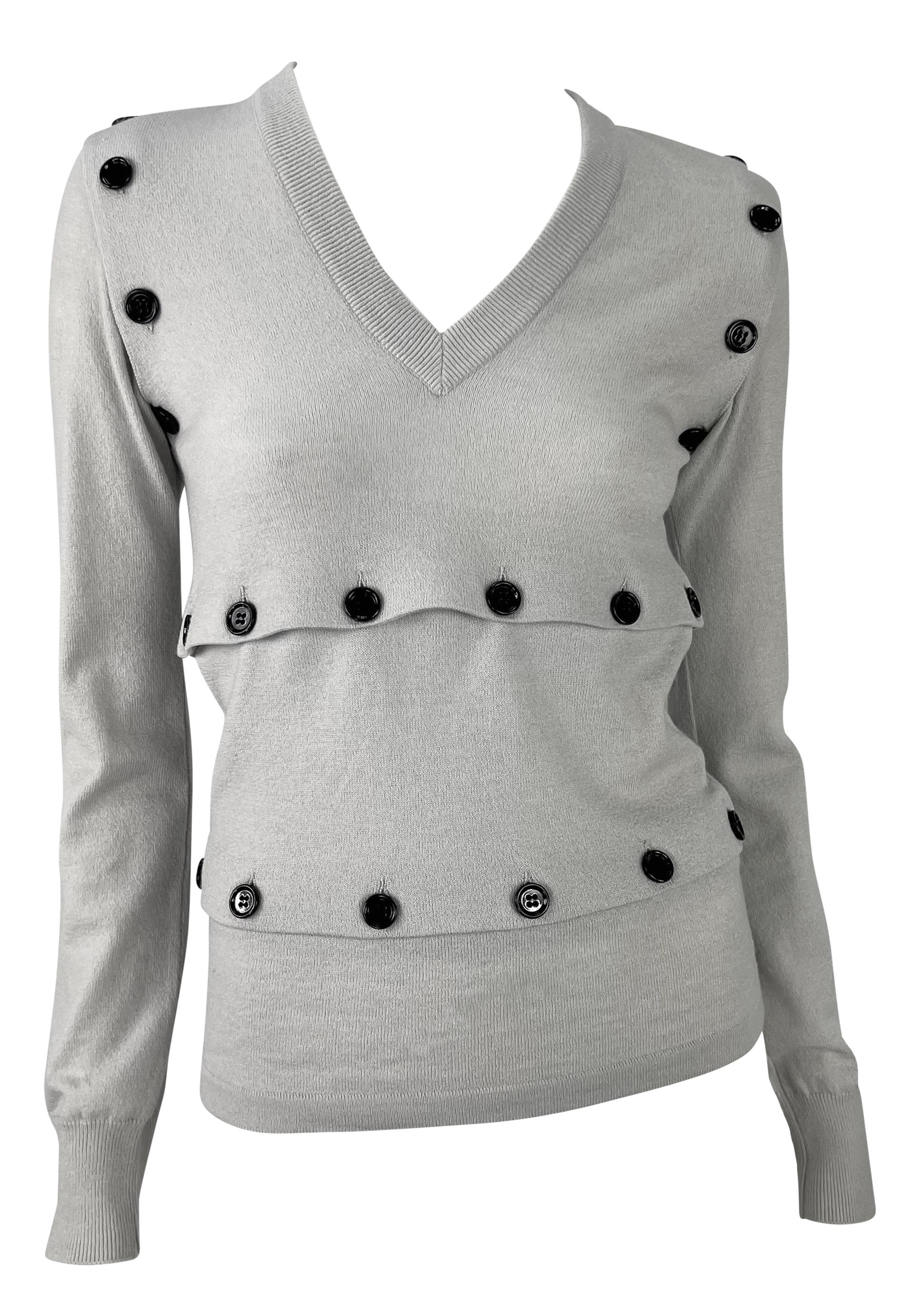 Cet incroyable pull convertible gris de Dolce & Gabbana, issu de la collection automne/hiver 2003, présente un col en V et est orné de gros boutons noirs fonctionnels. Ces boutons permettent de styliser le pull de nombreuses façons, offrant ainsi