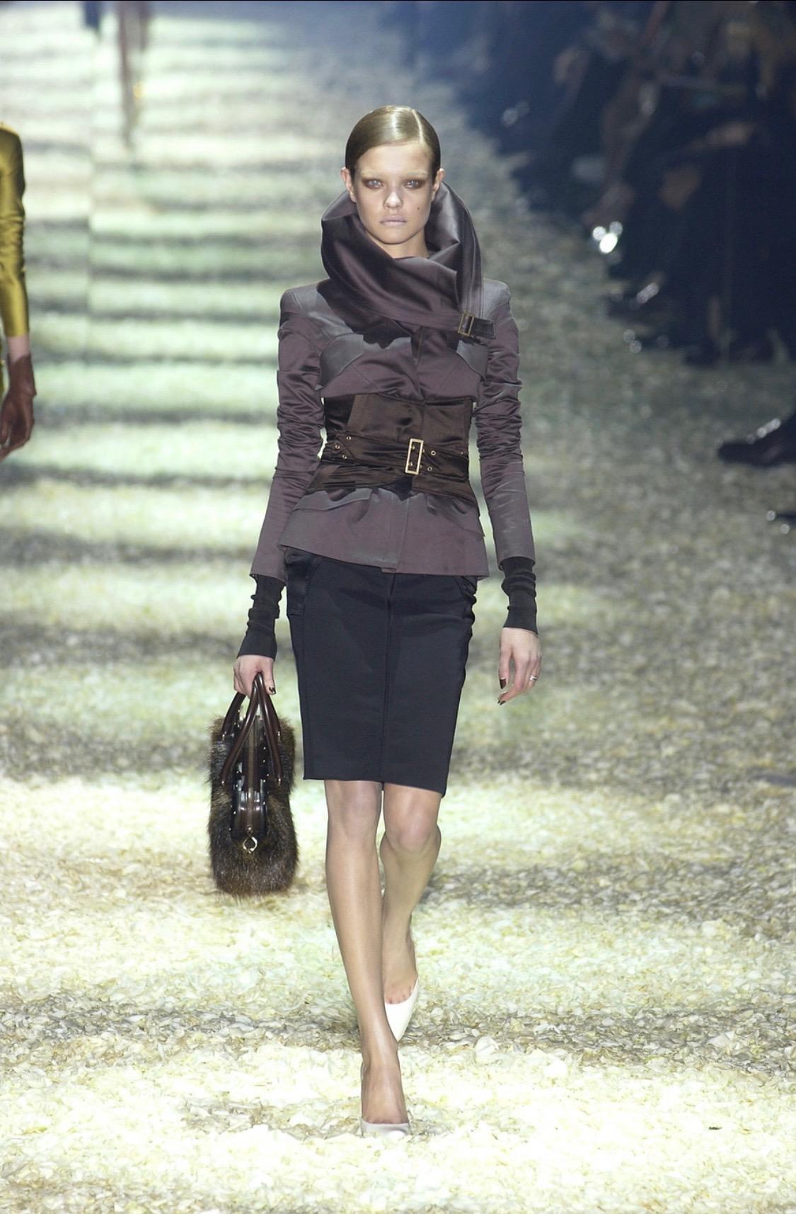 Presenting a stretch black satin Gucci skirt, designed by Tom Ford. From the Fall/Winter 2003 collection, this beautiful skirt features zippers on either hip and paneling which enhances the curves of the female form. This skirt debuted on the runway