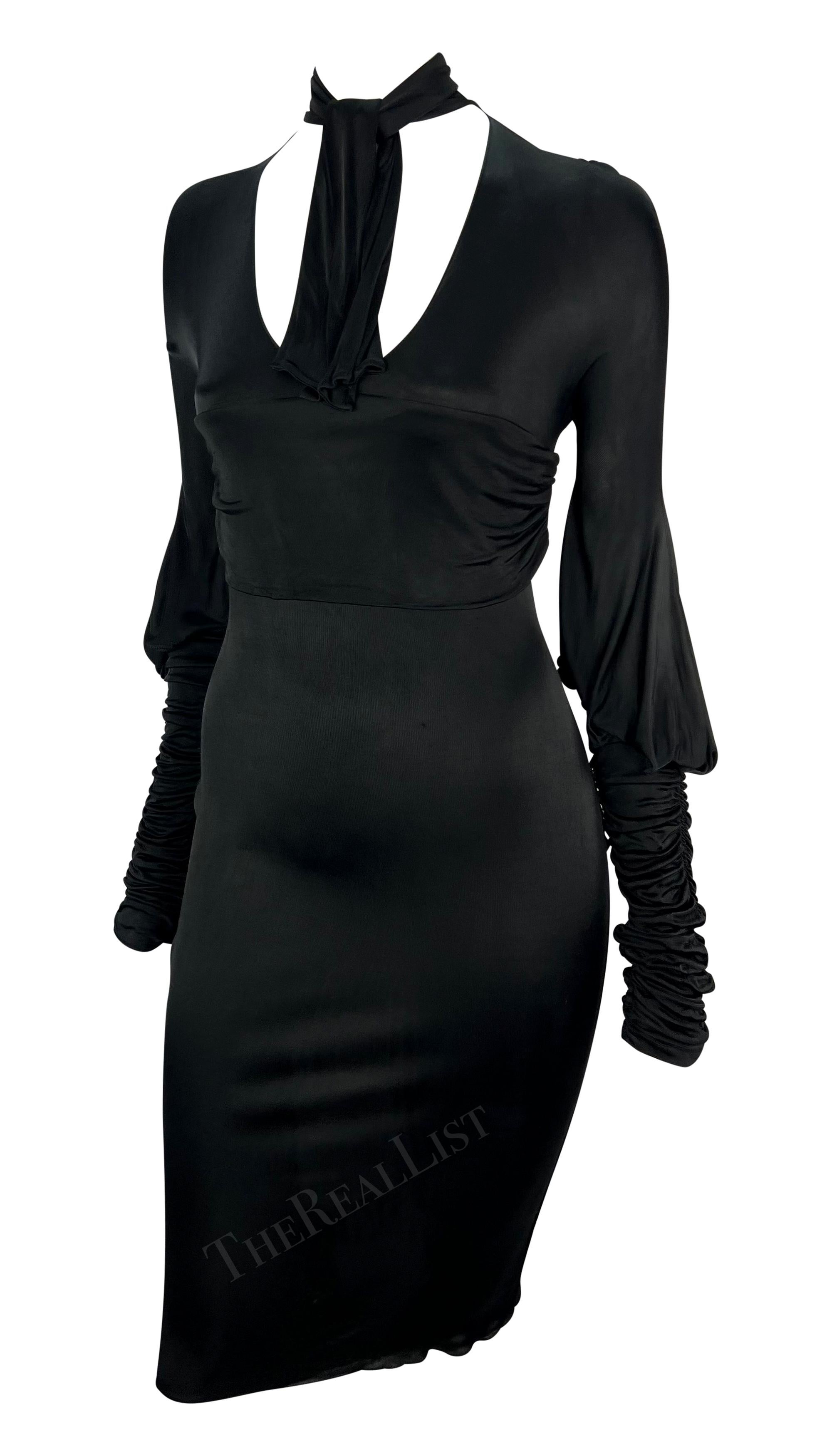 This black Gucci mini dress, designed by Tom Ford, is from the Fall/Winter 2003 collection. Made of stretch fabric, it features a deep v-neckline and a pussy cat bow. The long sleeves are ruched and fitted at the forearm, with fabric billowing at