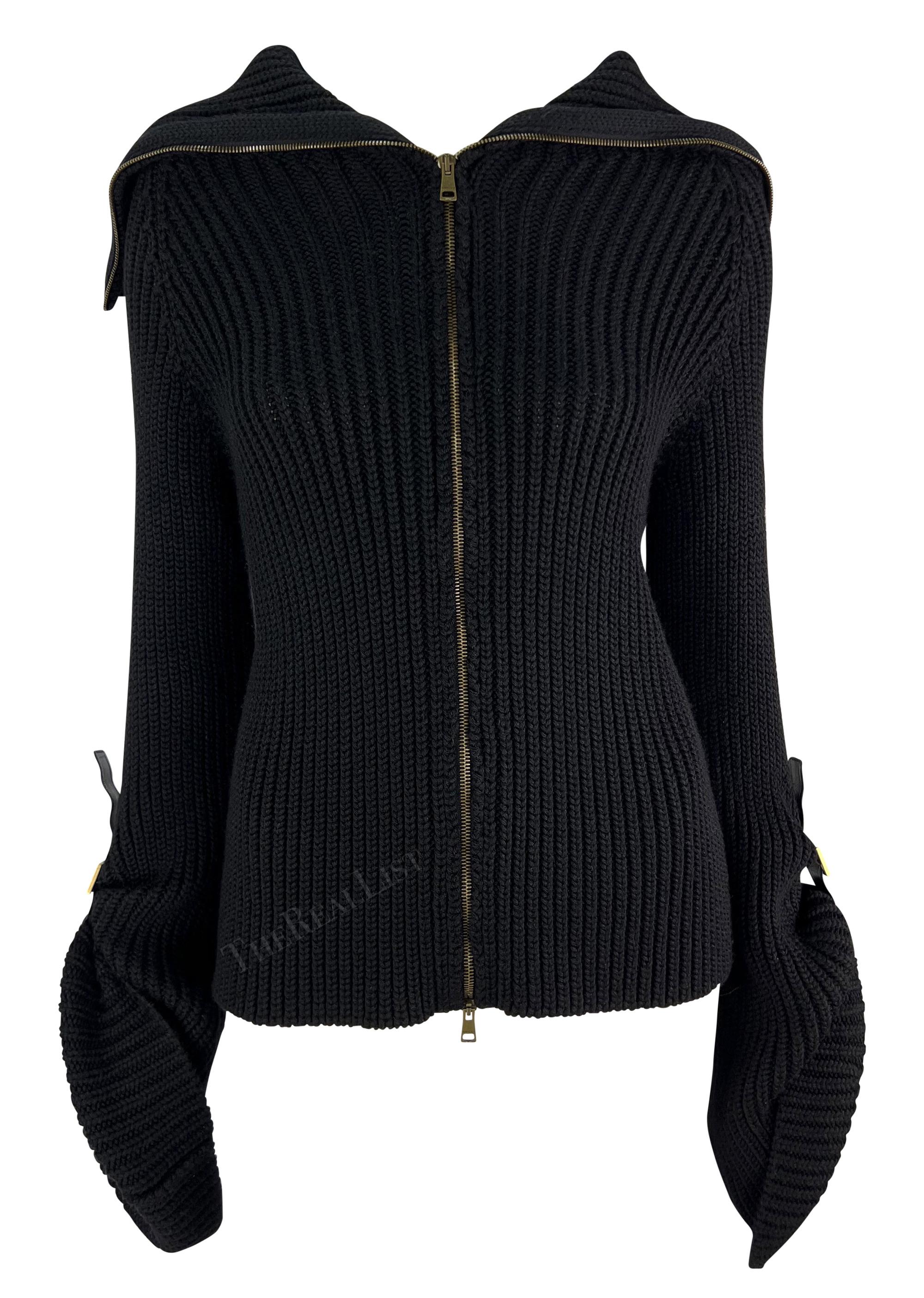 TheRealList presents: a fabulous black knit Gucci sweater, designed by Tom Ford. From the Fall/Winter 2003 collection, this stylish sweater has a front zip-up closure, a fold-over collar with a leather buckle, and eye-catching large bell sleeves.