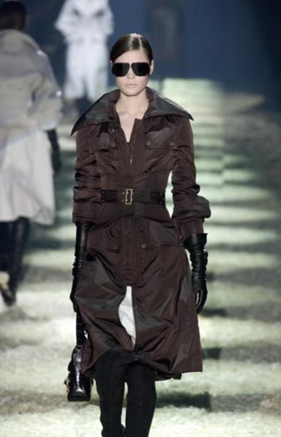 Tom Ford designed this olive green puffer jacket for Gucci's Fall/Winter 2003 collection. This sophisticated winter essential made its debut as Look 2 on the season's runway, modeled by Adina Fohlin. The down-filled puffer jacket falls below the