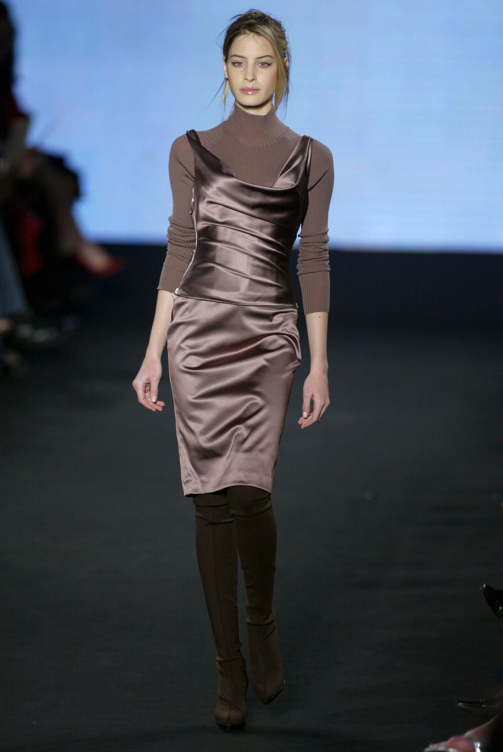 De la colección Otoño/Invierno 2003 de Stella McCartney, este vestido de cóctel negro está confeccionado en satén elástico con un suave brillo. El corpiño presenta un espectacular escote de pico y un corsé interno para dar soporte y forma. Una