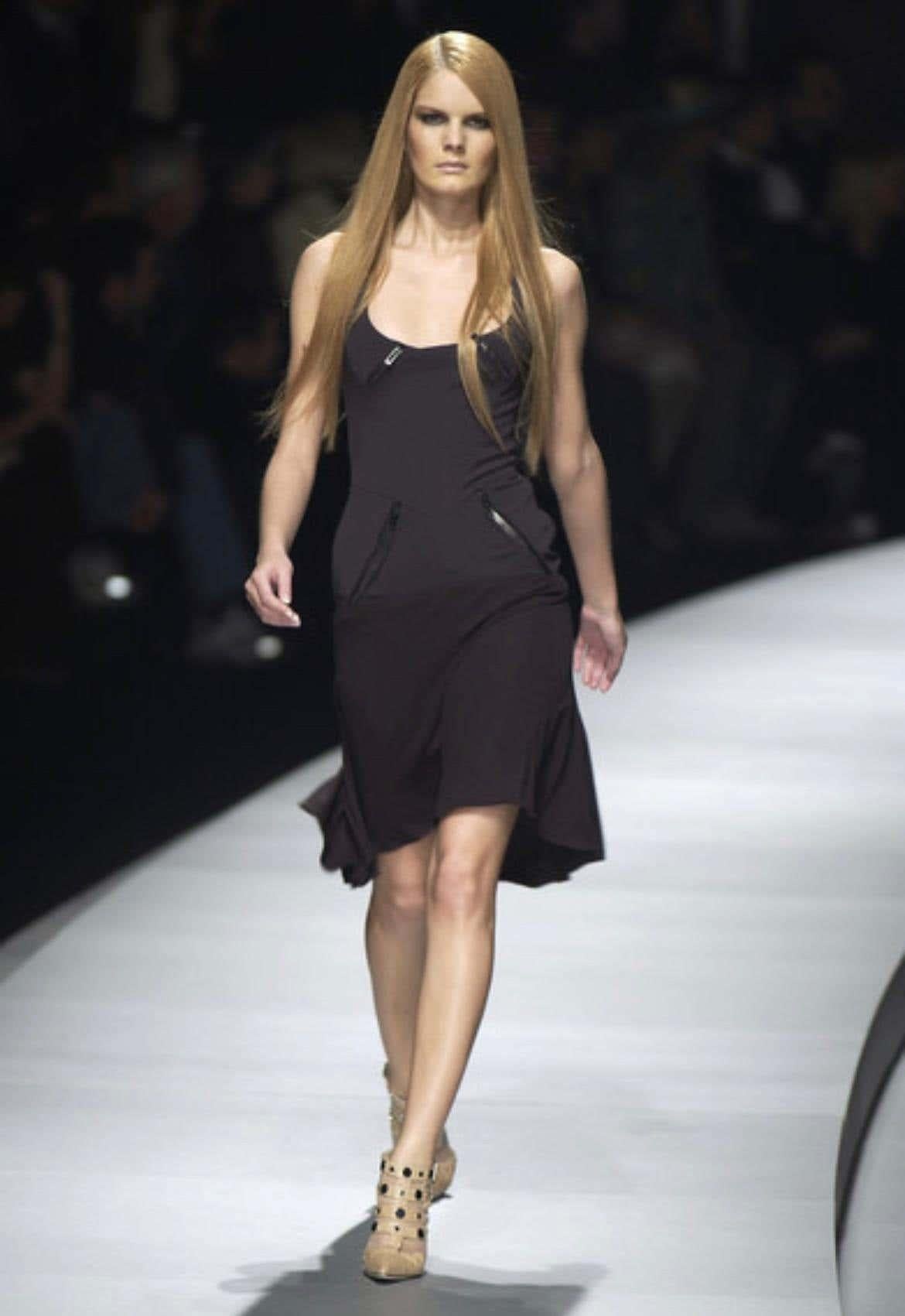 Présentation d'une fabuleuse mini robe noire Versace, créée par Donatella Versace. Issue de la collection Automne/Hiver 2003, cette robe a fait ses débuts sur le défilé de la saison en tant que look 25. Elle présente une encolure dégagée, un ourlet