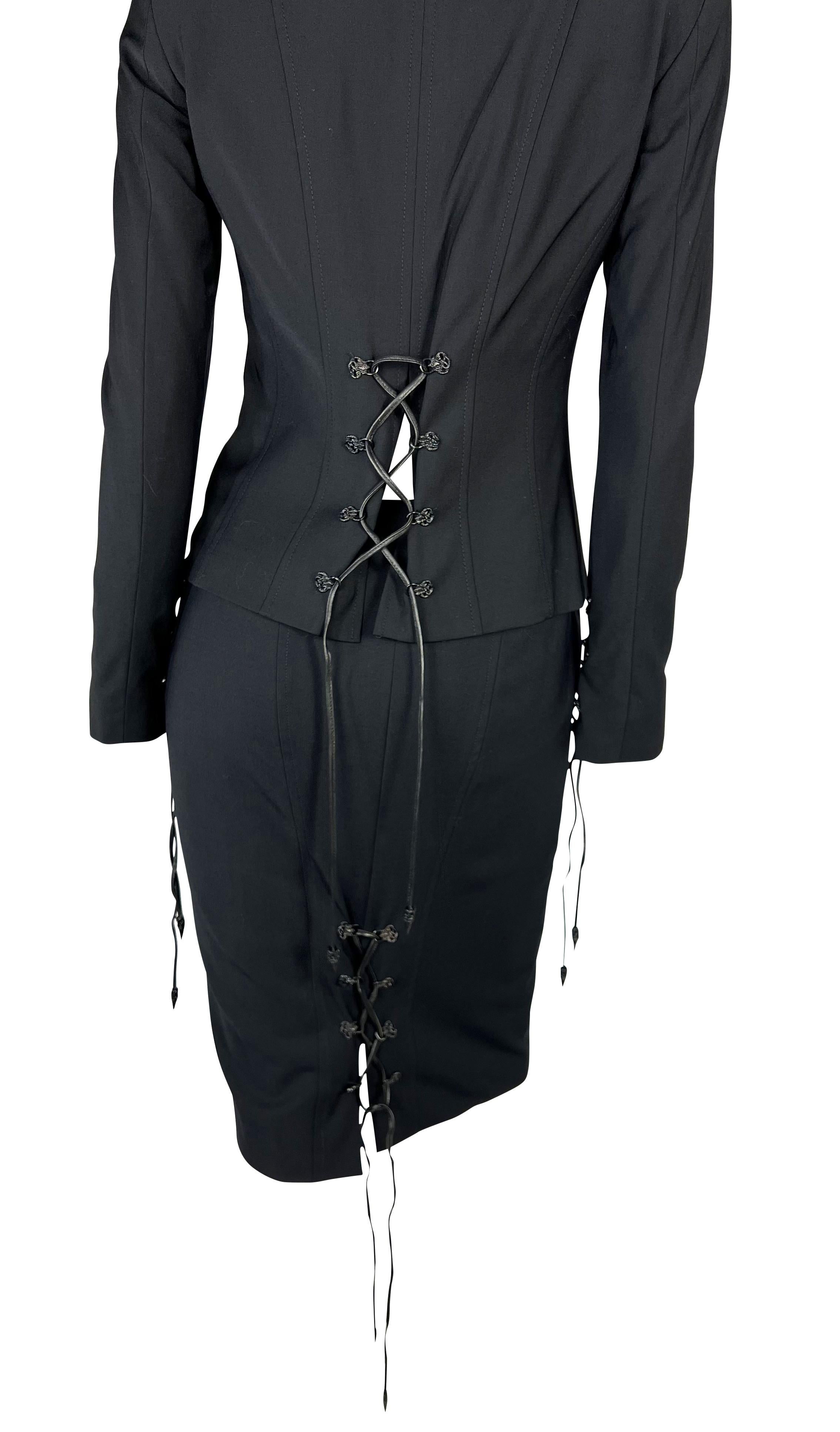 Nous vous présentons un incroyable ensemble de tailleur jupe Versace noir à lacets, dessiné par Donatella Versace. Issu de la collection automne/hiver 2003, ce fabuleux ensemble se compose d'une veste zippée noire et d'une jupe assortie. La veste