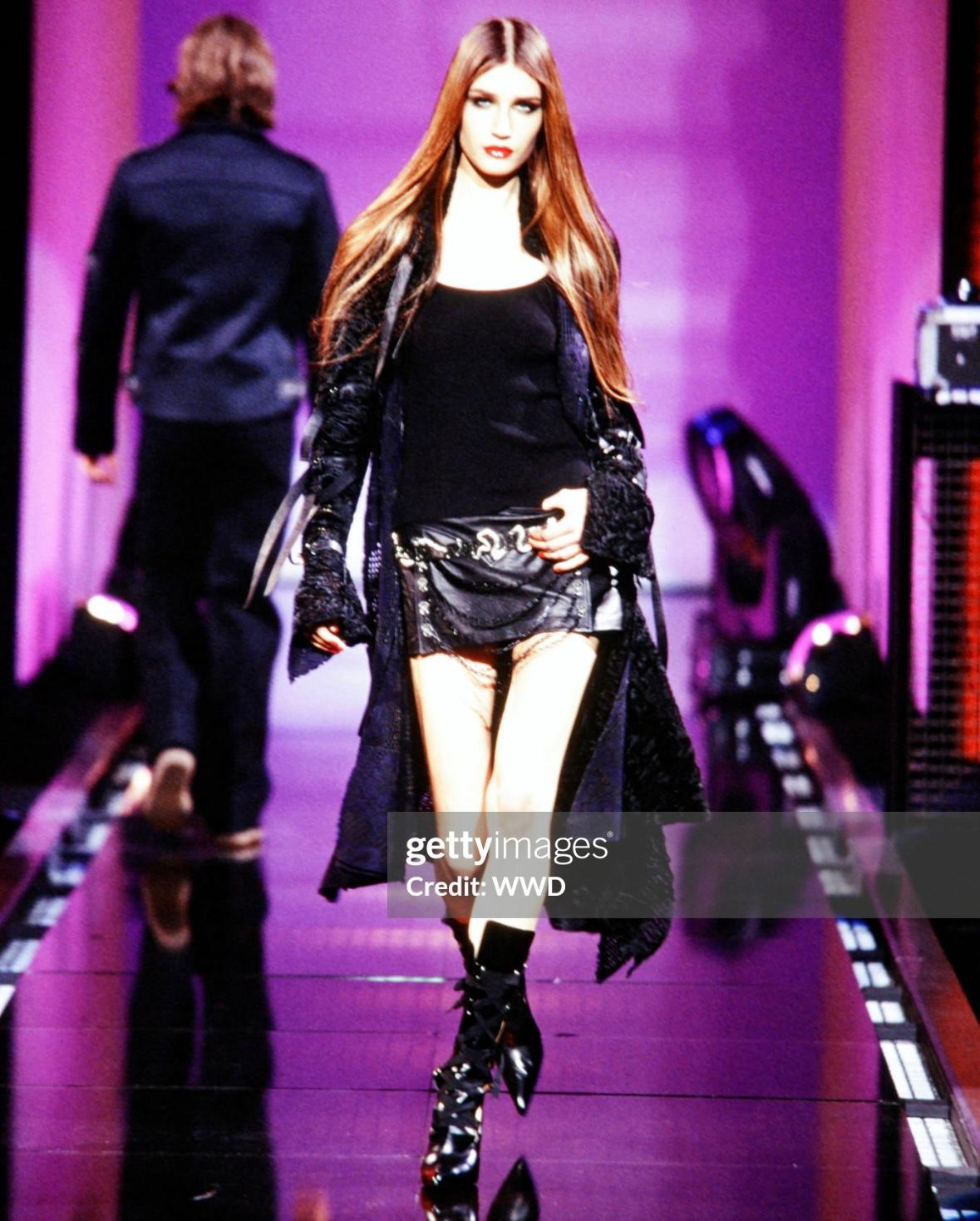 Présentation d'une fabuleuse mini-jupe en cuir noir Versace, créée par Donatella Versace. Issue de la collection automne/hiver 2003, cette mini-jupe est entièrement construite en cuir noir et une version a été présentée sur le podium de la saison.