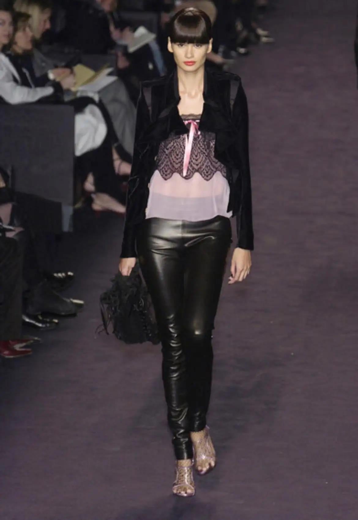 This pink and black lace tank top from Yves Saint Laurent Rive Gauche, designed by Tom Ford for Fall/Winter 2003, debuted on the runway as look 18. Crafted from sheer light pink chiffon with a lace overlay, it features spaghetti straps and a hot