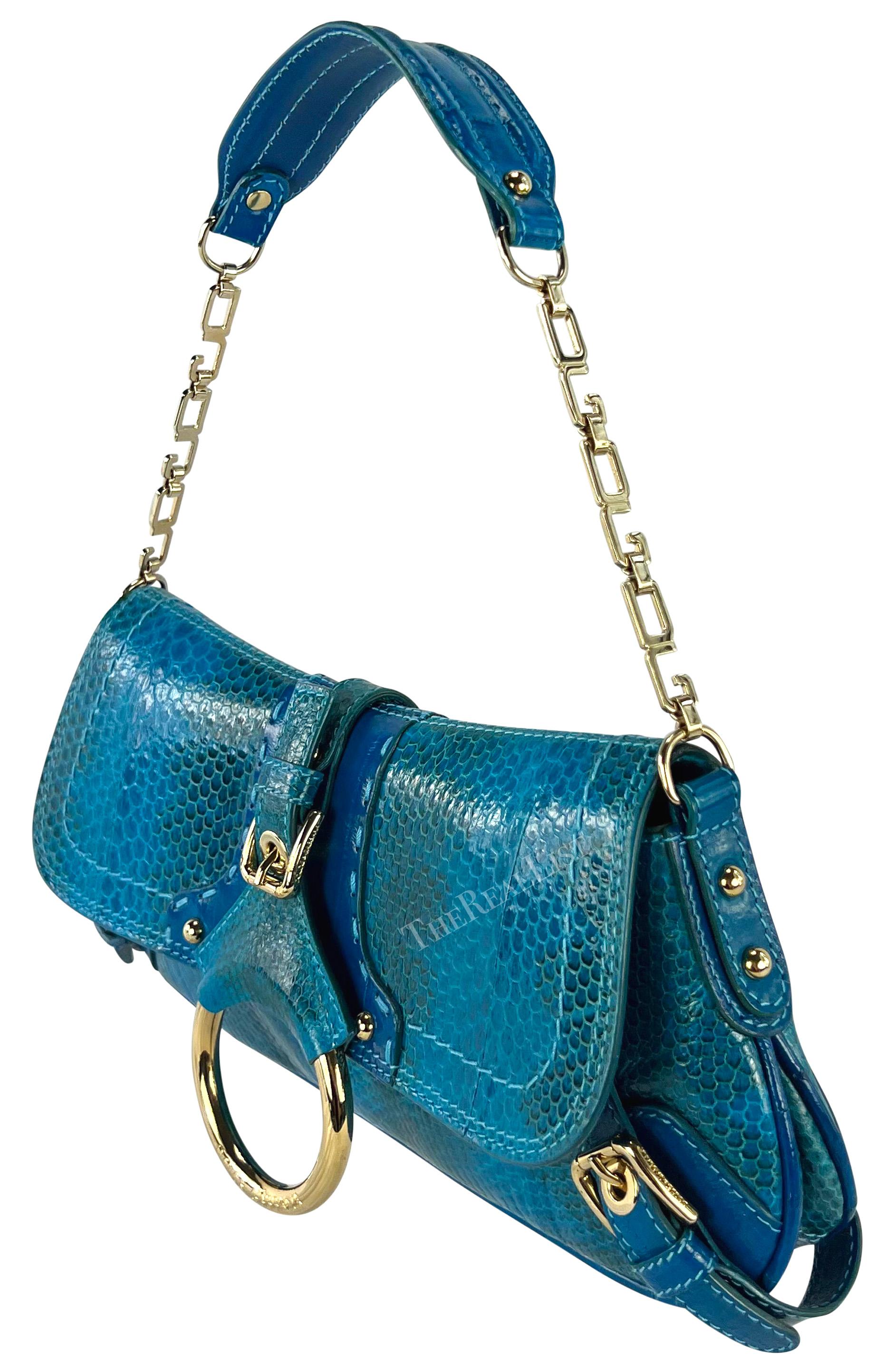 From the Fall/Winter 2004 collection, this fabulous bright blue python embossed Dolce & Gabbana shoulder bag is constructed primarily of vibrant blue python skin with blue eel skin accents. This flap bag features gold-tone hardware with a 'DG' chain