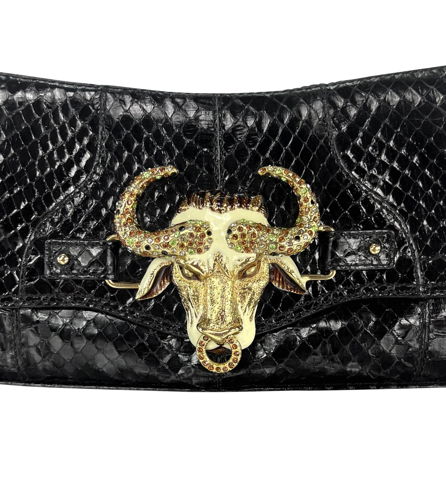 Presenting a black snakeskin Dolce & Gabbana horoscope shoulder bag from the Fall/Winter 2004 collection. This astrology-inspired flap bag is crafted from black python skin and features an enamel and rhinestone Taurus bull head buckle. The bag is