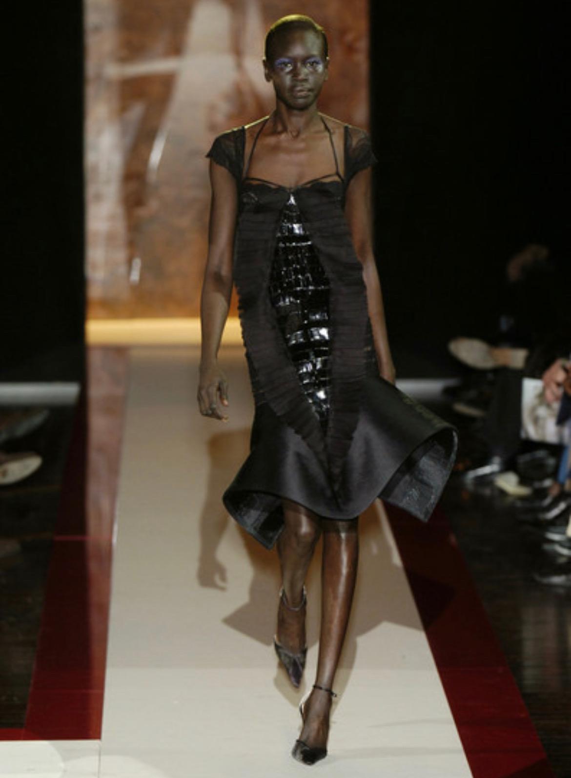 Ich präsentiere ein unglaubliches schwarzes Spitzenkleid von Gianfranco Ferre. Dieses Kleid aus der Herbst/Winter-Kollektion 2004 wurde zum ersten Mal auf dem Laufsteg präsentiert und von Alek Wek modelliert. Das Kleid hat Spitzenblütenärmel, einen