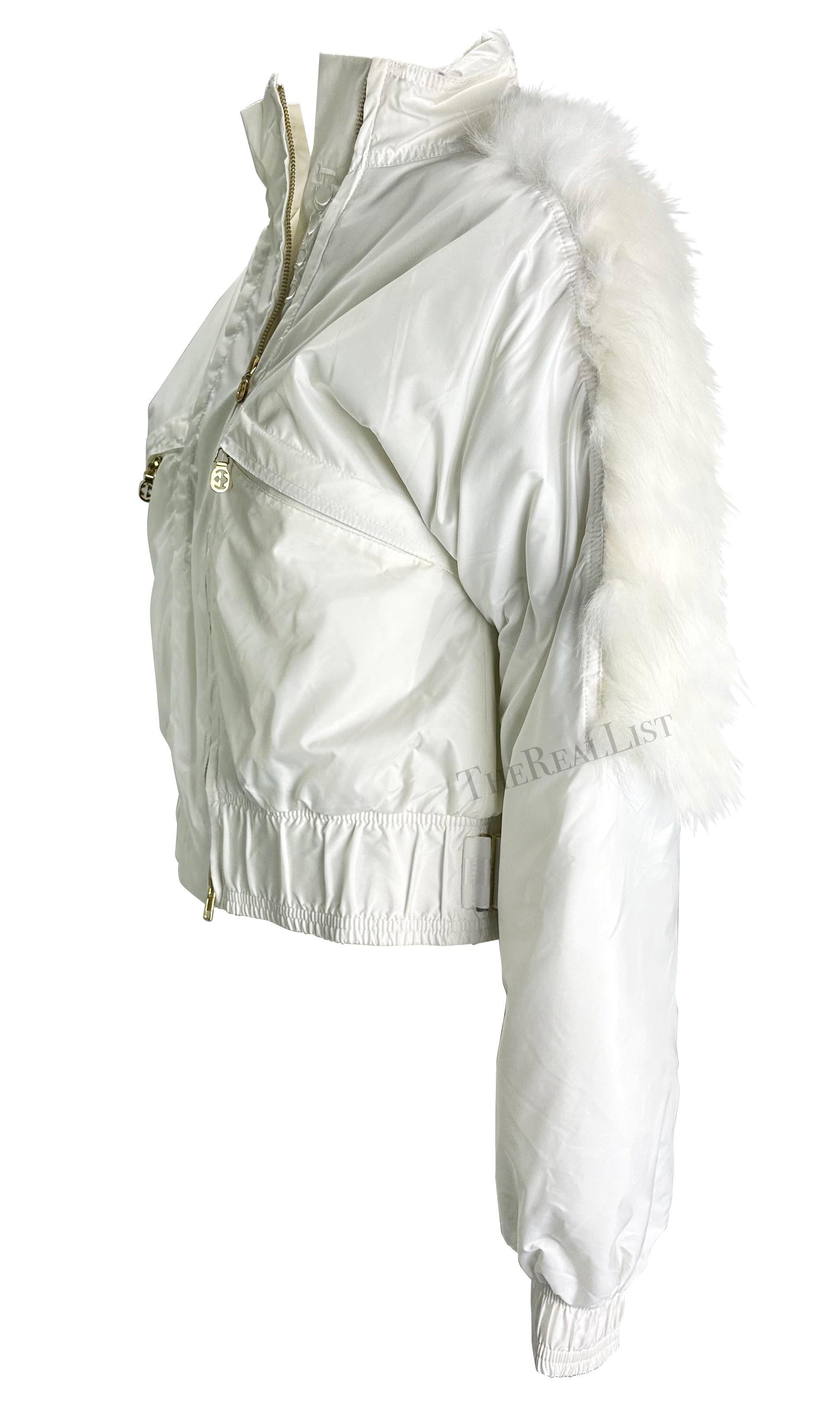 Ich präsentiere eine wunderschöne weiße Gucci-Pufferjacke, entworfen von Tom Ford. Diese Winterjacke aus der Herbst/Winter-Kollektion 2004 verfügt über einen Pelzbesatz, ein gesticktes Gucci-Logo, goldfarbene GG-Hardware und eine versteckte Kapuze.