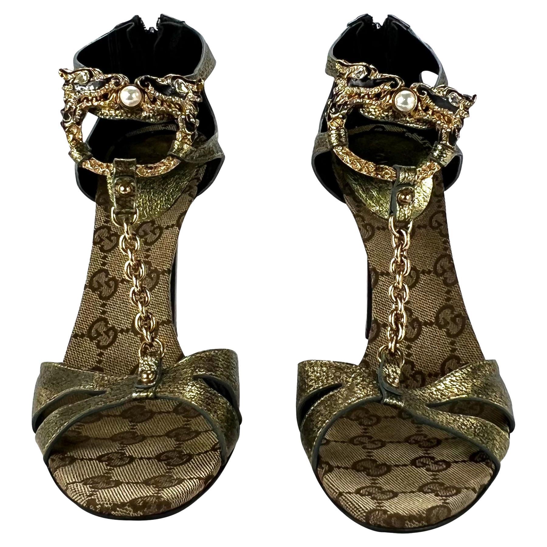 Presenting a pair of stunning gold leather Gucci dragon heels, designed by Tom Ford. From the Fall/Winter 2004 collection, these strap heels feature a Gucci 'GG' monogram insole and an interlocking metal dragon made complete with enamel, rhinestone,