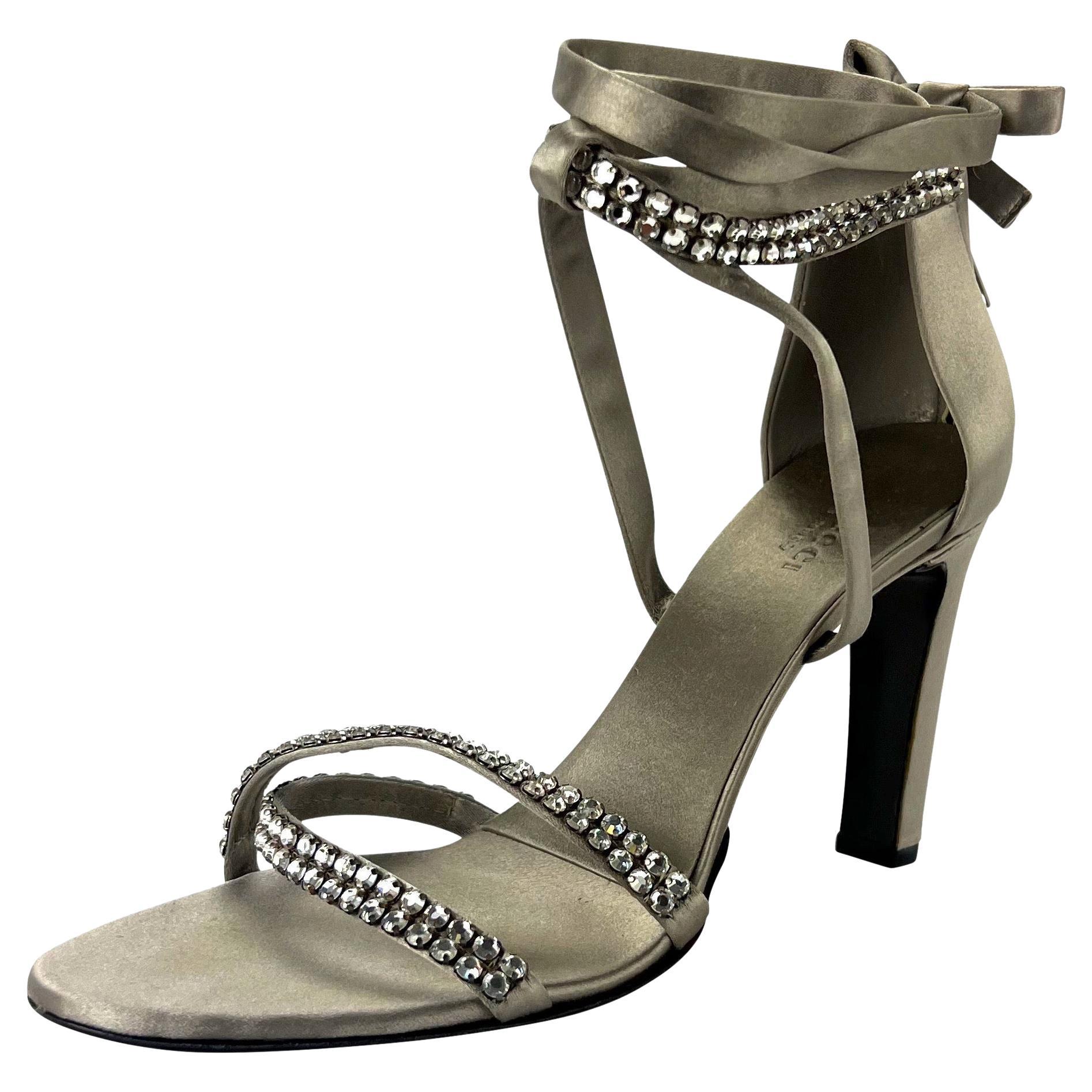 Presenting a fabulous pair of silver silk satin Gucci sandal heels designed by Tom Ford. From the Fall/Winter 2004 collection, these slingback heels are complete with rhinestone accented toe straps and ankle lace ties. 

Additional Measurements: