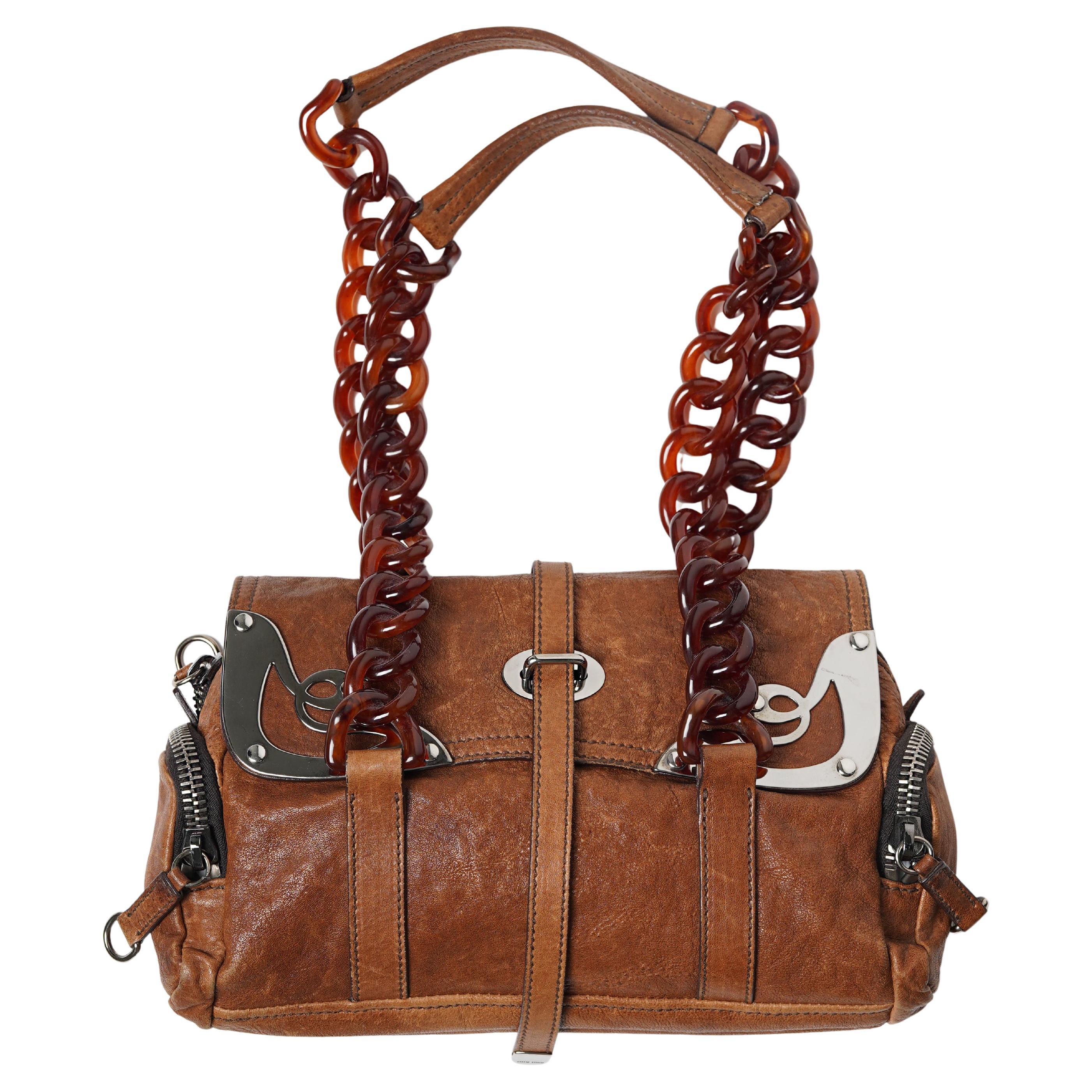 Presentamos un bolso de pasarela Miu Miu excepcionalmente raro de la colección Otoño/Invierno 2004, una temporada de culto que definió la estética de la marca a principios de la década de 2000. Visto en la pasarela, este escultural diseño de asa