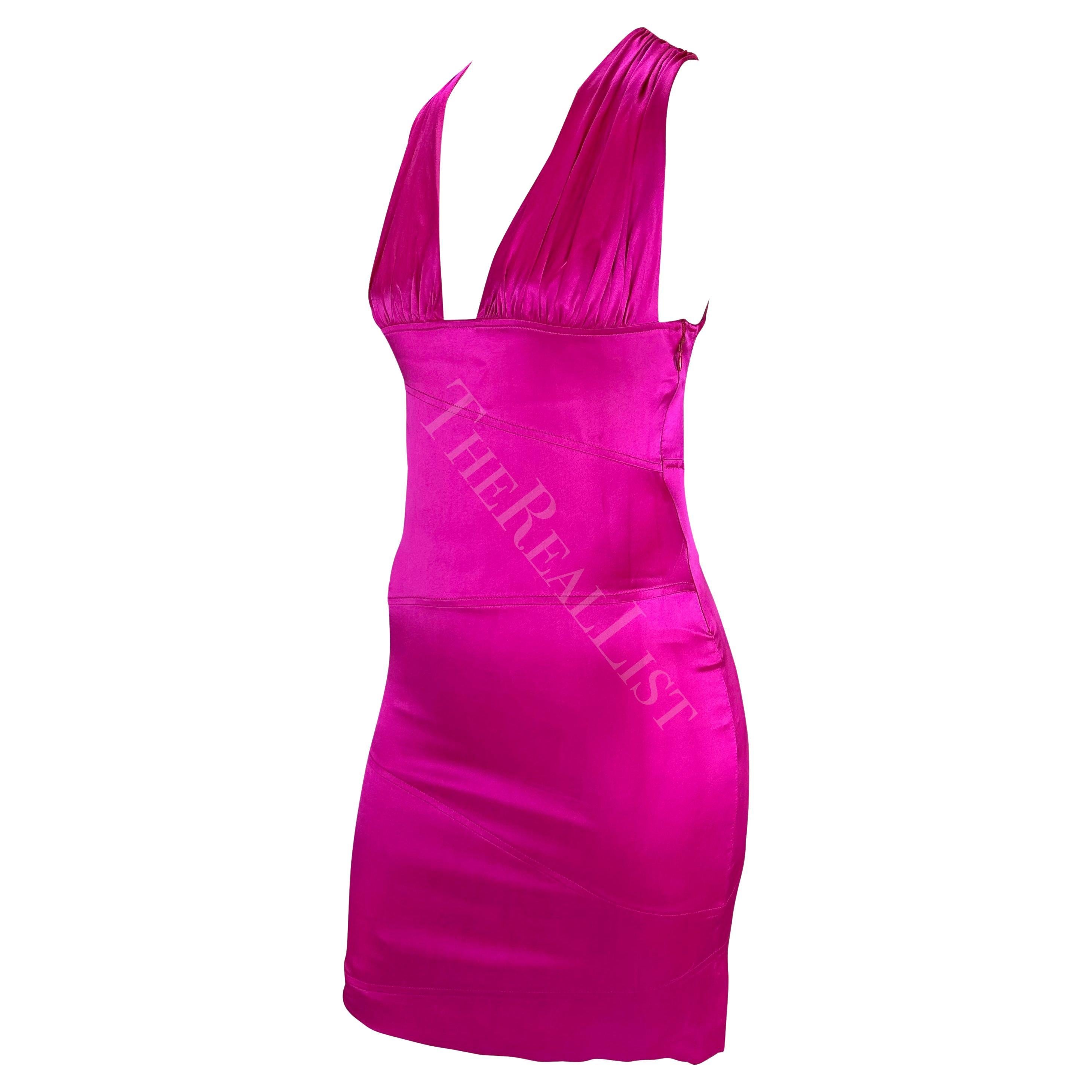 Presenting a striking hot pink backless bodycon dress designed by Donatella Versace for Versace's Fall/Winter 2004 collection. Ruching at the bust accentuates the sexy plunging neckline and asymmetric paneling perfectly hugs the body. Check out our