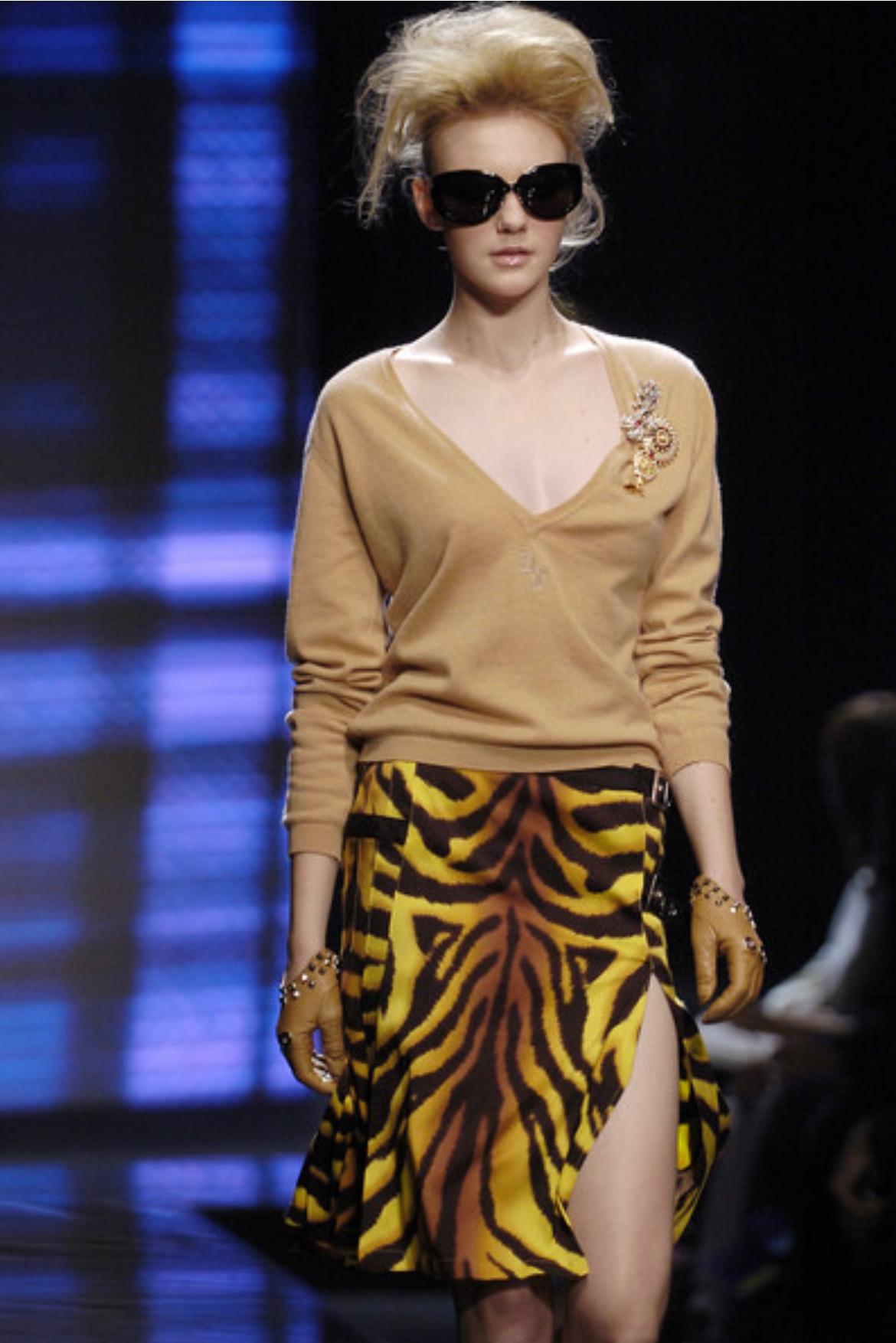 Wir präsentieren einen auffälligen gelben Versace-Rock mit Tiger-Print, entworfen von Donatella Versace. Ein ähnlicher Rock aus der Herbst/Winter-Kollektion 2004 wurde auf dem Laufsteg der Saison in Look 8 von Caroline Trentini vorgeführt. Das