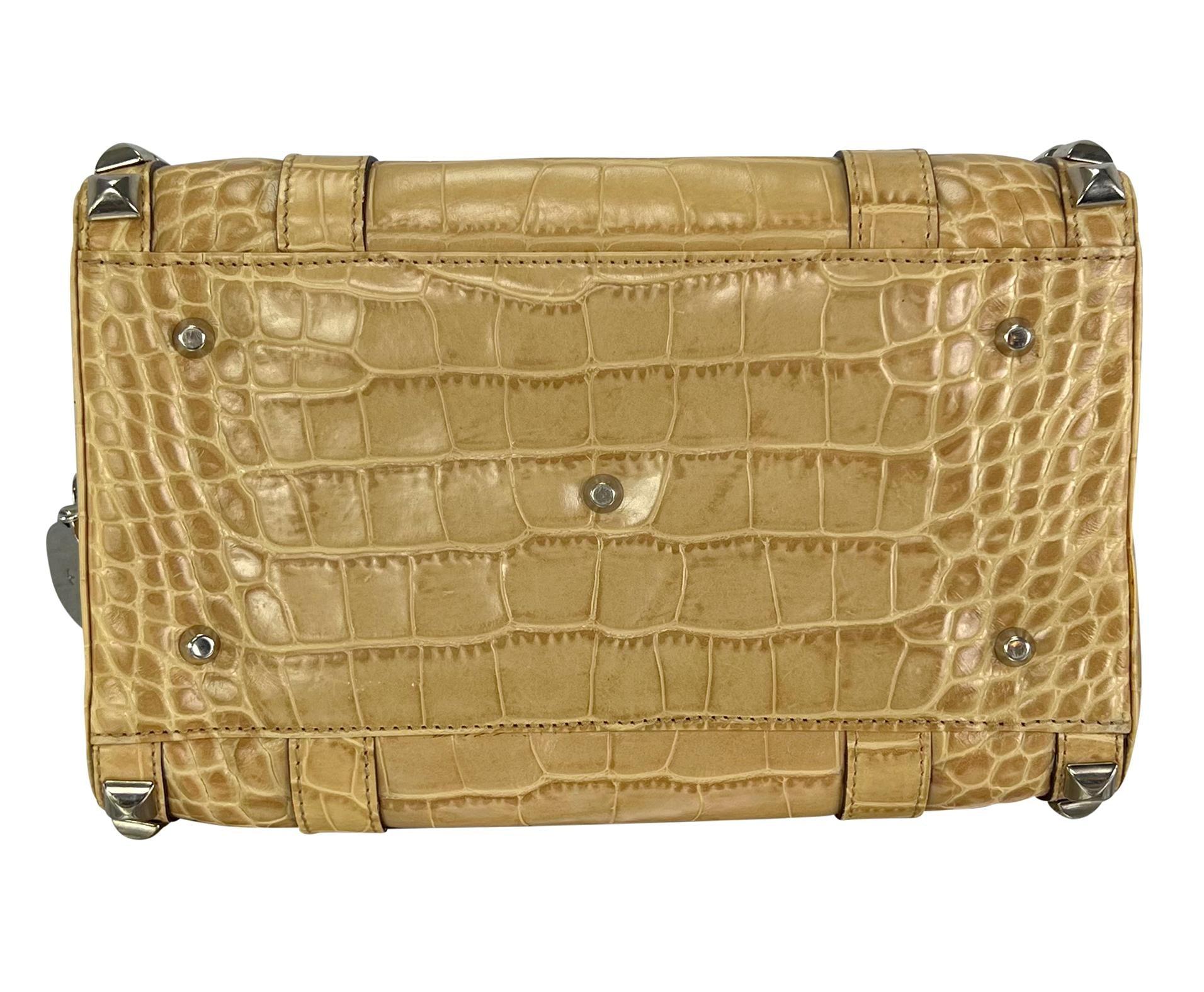 Conçu par Donatella Versace pour la collection automne/hiver 2004 de la maison, ce chic sac beige de style Boston est orné d'un remarquable motif de crocodile gaufré. Le sac est orné de clous pyramidaux argentés qui encadrent le design, complétés